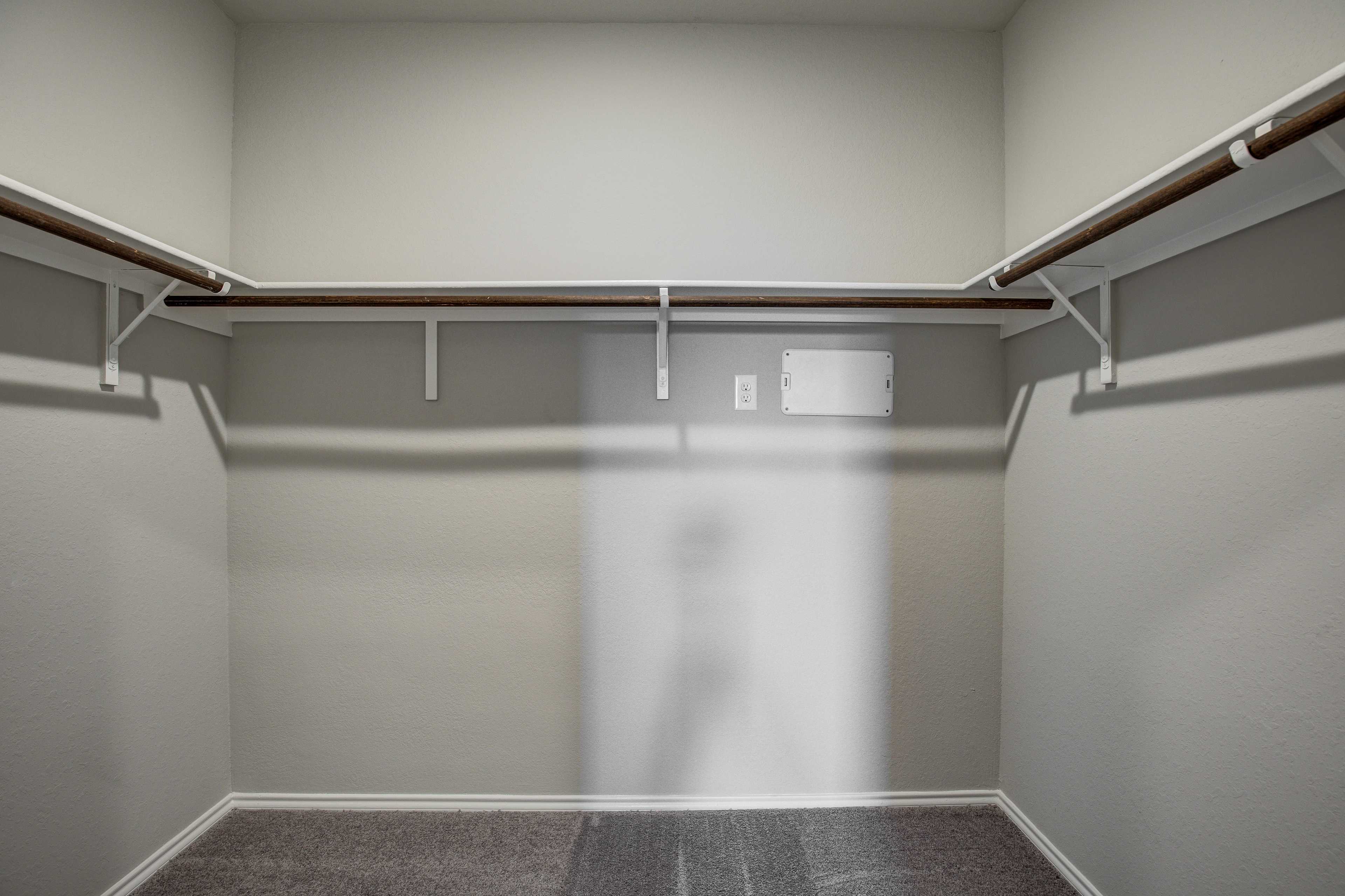 Spacious walk-in closet in The Blanco B master suite with beige walls, wooden shelves, hanging rods, and carpeted floor