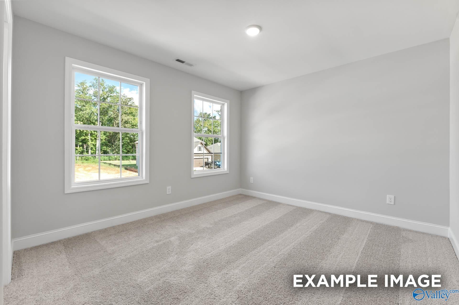 Bright secondary bedroom with light gray walls, large sunny windows, and beige carpet in Davidson Homes The Chelsea D, New Market, Alabama