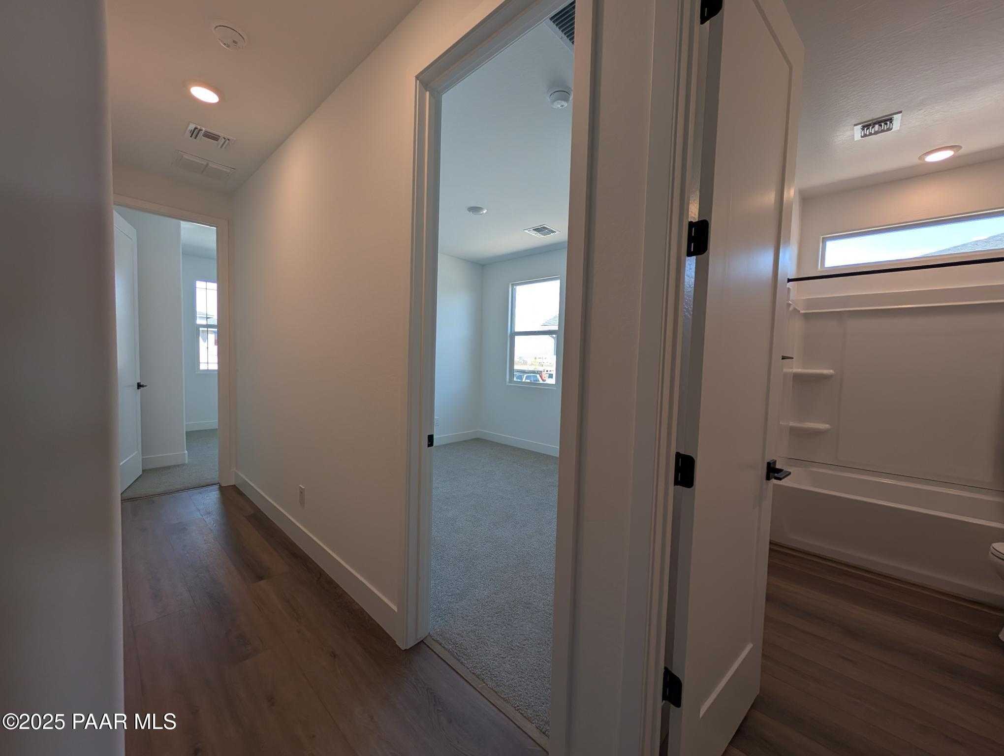 Bright hallway leading to carpeted bedroom and bathroom with tub in Davidson Homes The Sheridan II F, Prescott, Arizona