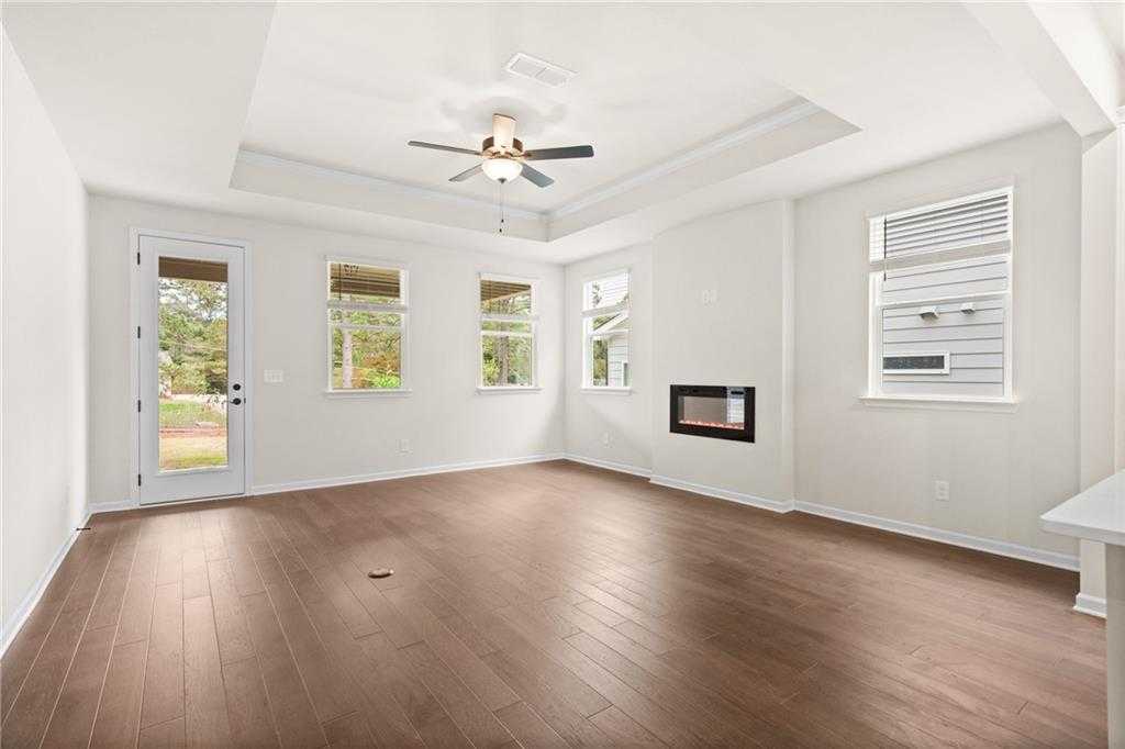 Bright living room with modern fireplace, ceiling fan, French doors to wooded backyard in Davidson Homes The Glenwood A, Loganville, GA