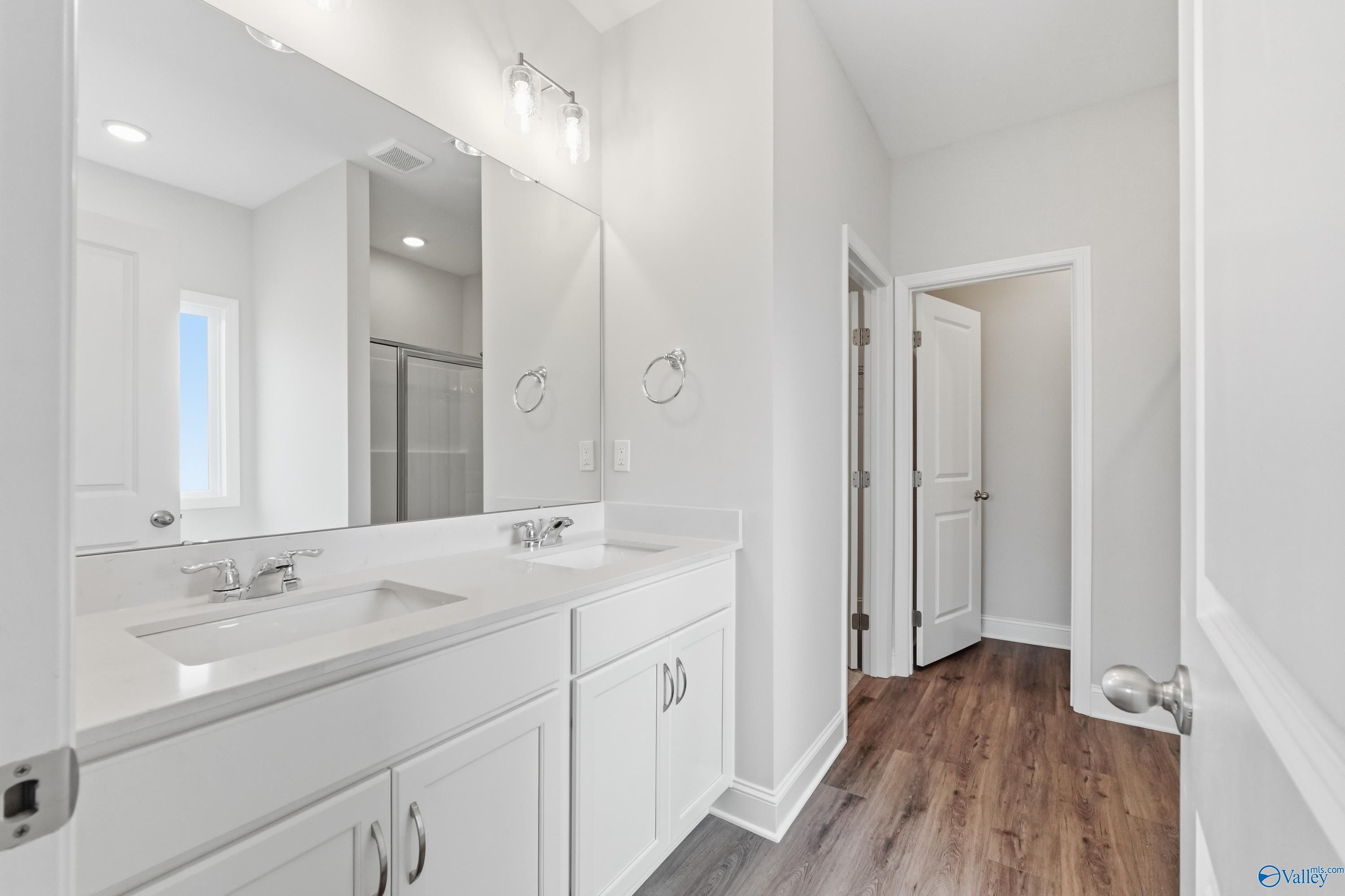 Modern master bathroom featuring double white vanity, large mirror, and glass shower in Davidson Homes The Daphne C, Toney, Alabama