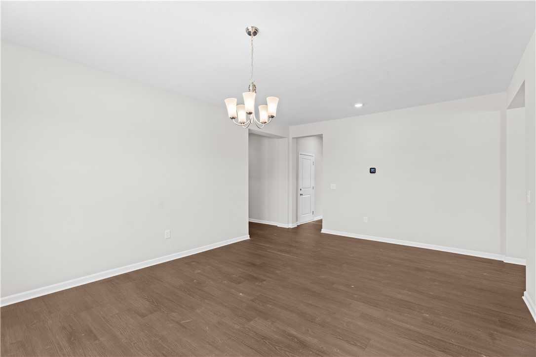 Elegant hallway with chandelier, white walls, and hardwood floors in Evermore Homes The Orion, Silver Oak, Cusseta, Alabama