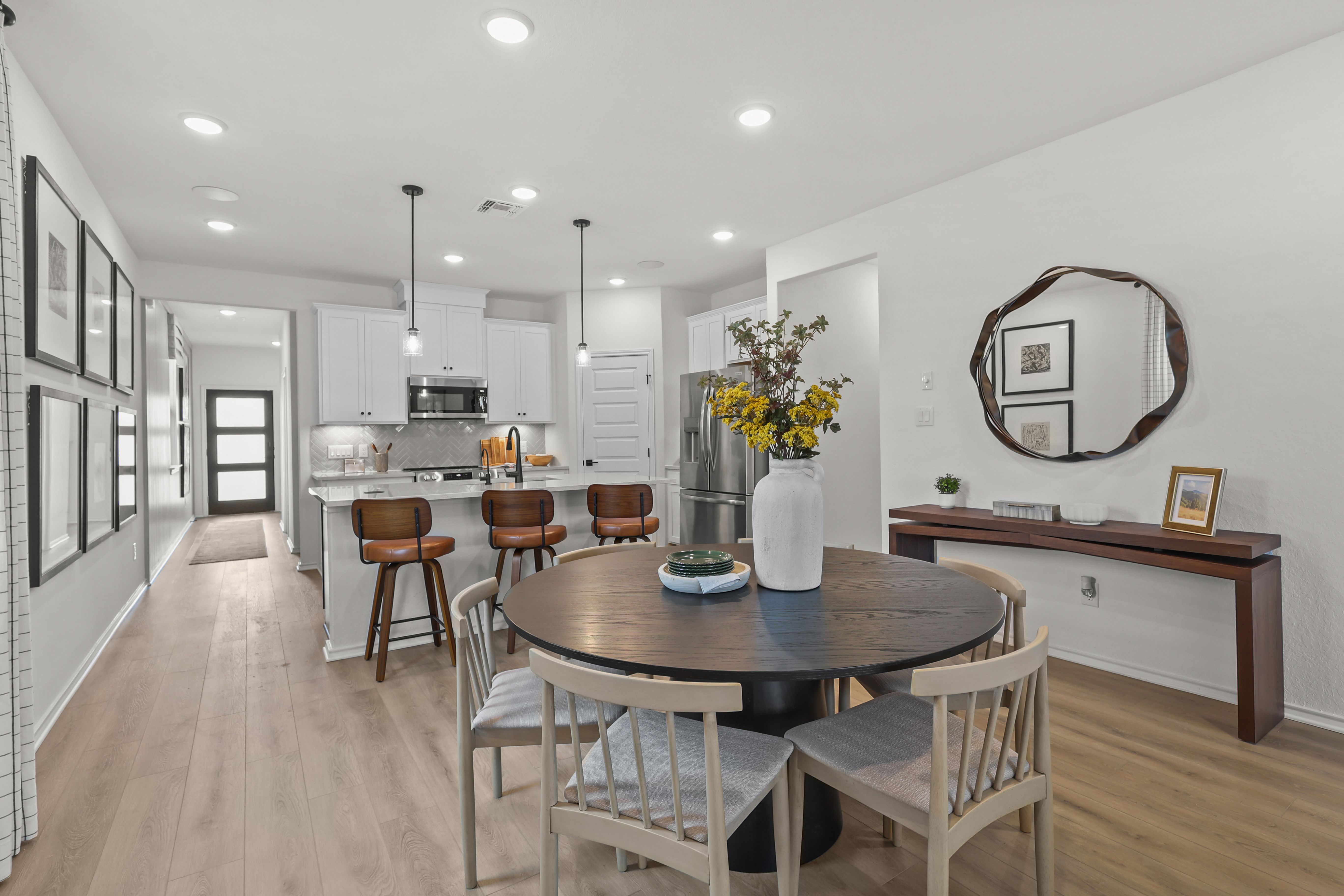 Kitchen with white cabinets opens to dining area in the decorated model home located in San Antonio, TX