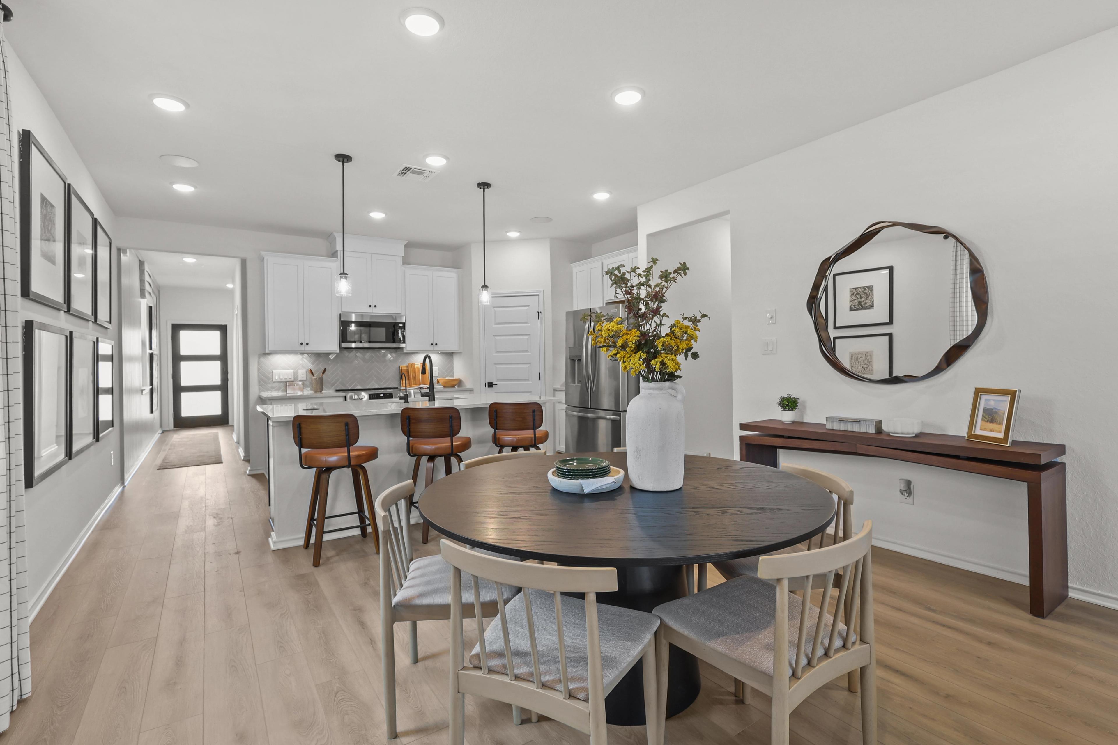 Kitchen with white cabinets opens to dining area in the decorated model home located in San Antonio, TX