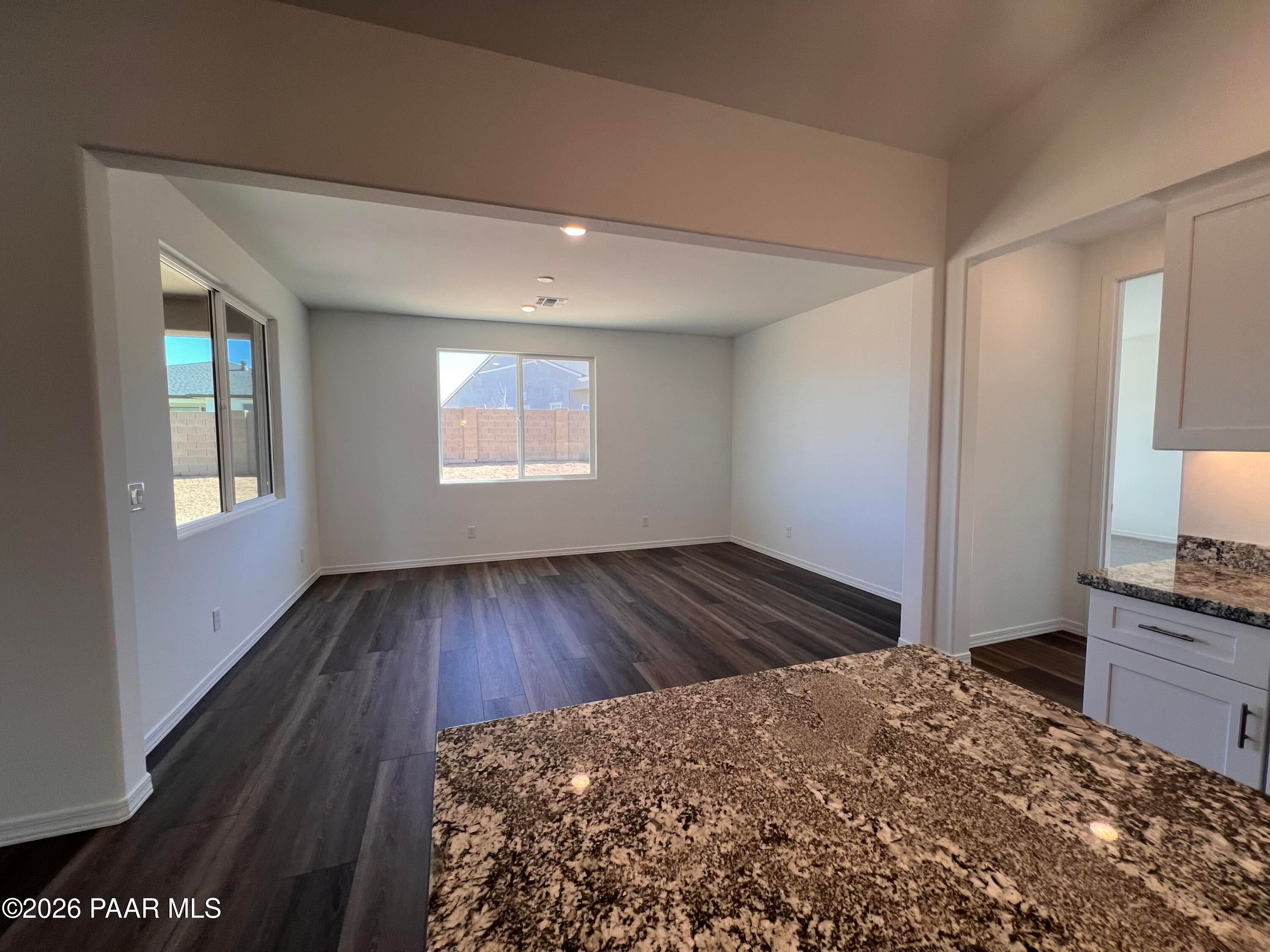 Spacious open-concept living and kitchen with granite counters, white cabinets, dark hardwood floors in Davidson Homes Sunrise II A, Prescott, AZ