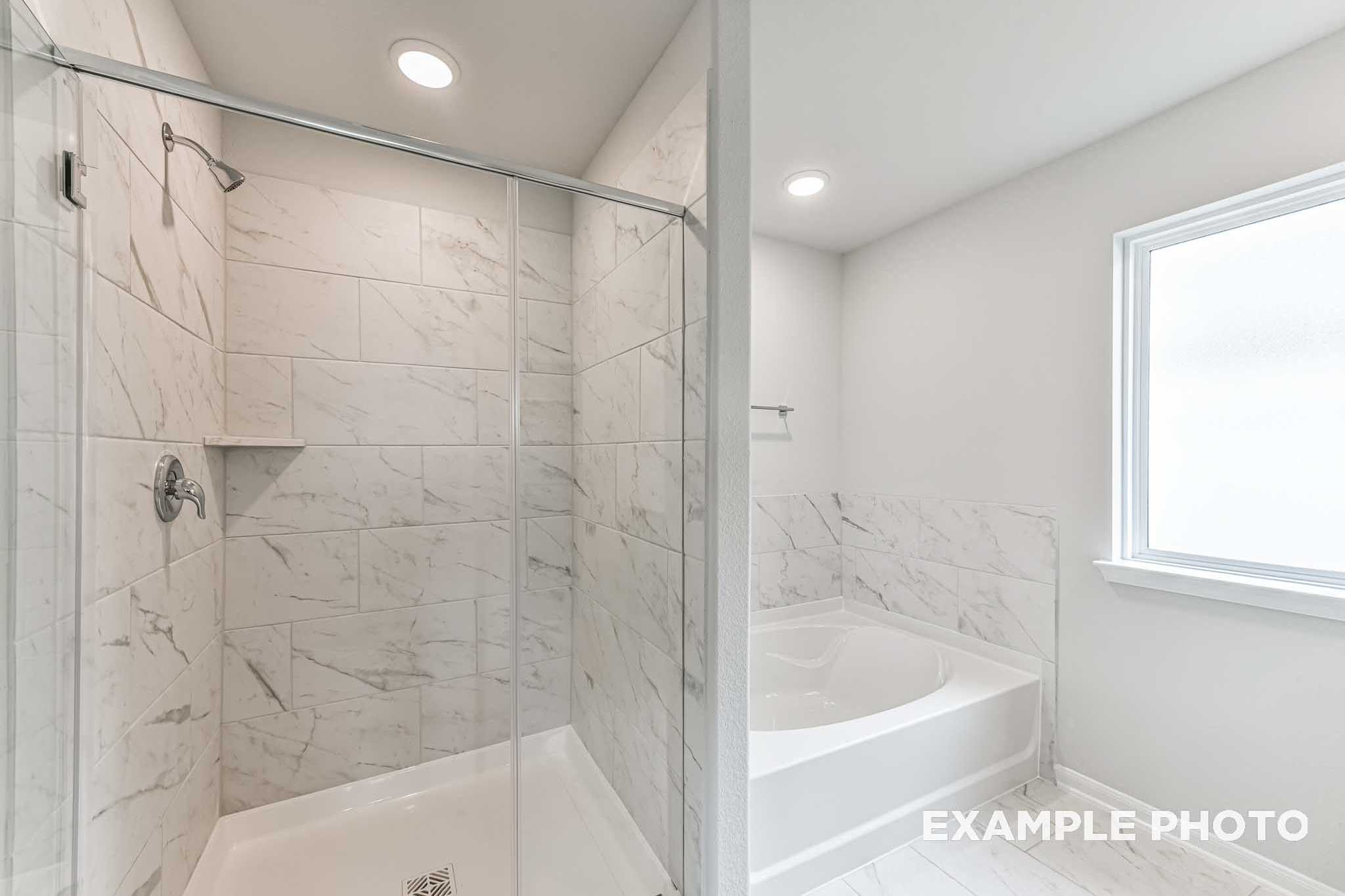 The Costa C master bath featuring glass shower with subway tile walls and adjacent soaking tub in Davidson Homes design
