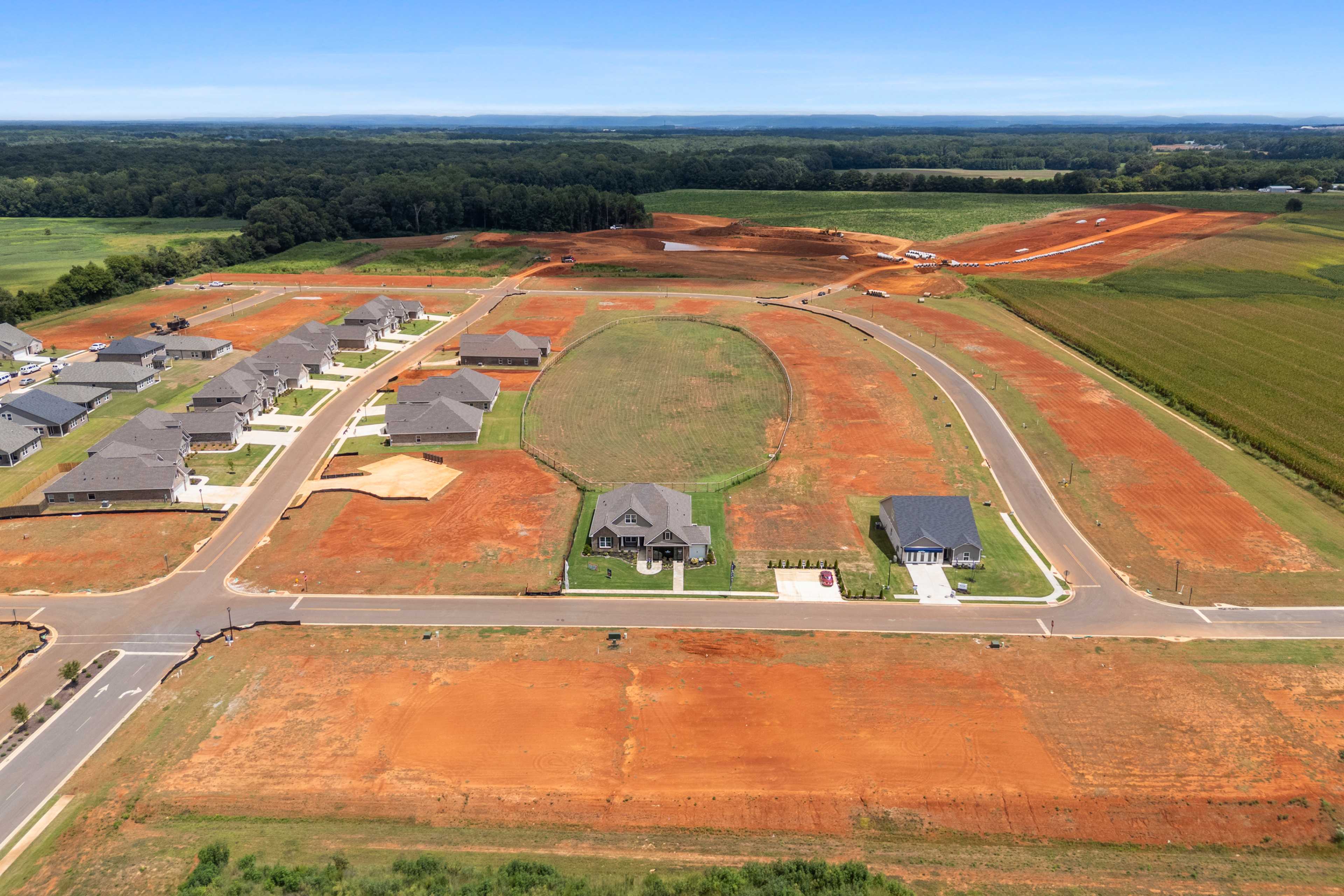 Aerial view of new homes in Kendall Farms Toney Alabama by Davidson Homes amid red dirt roads and surrounding green fields