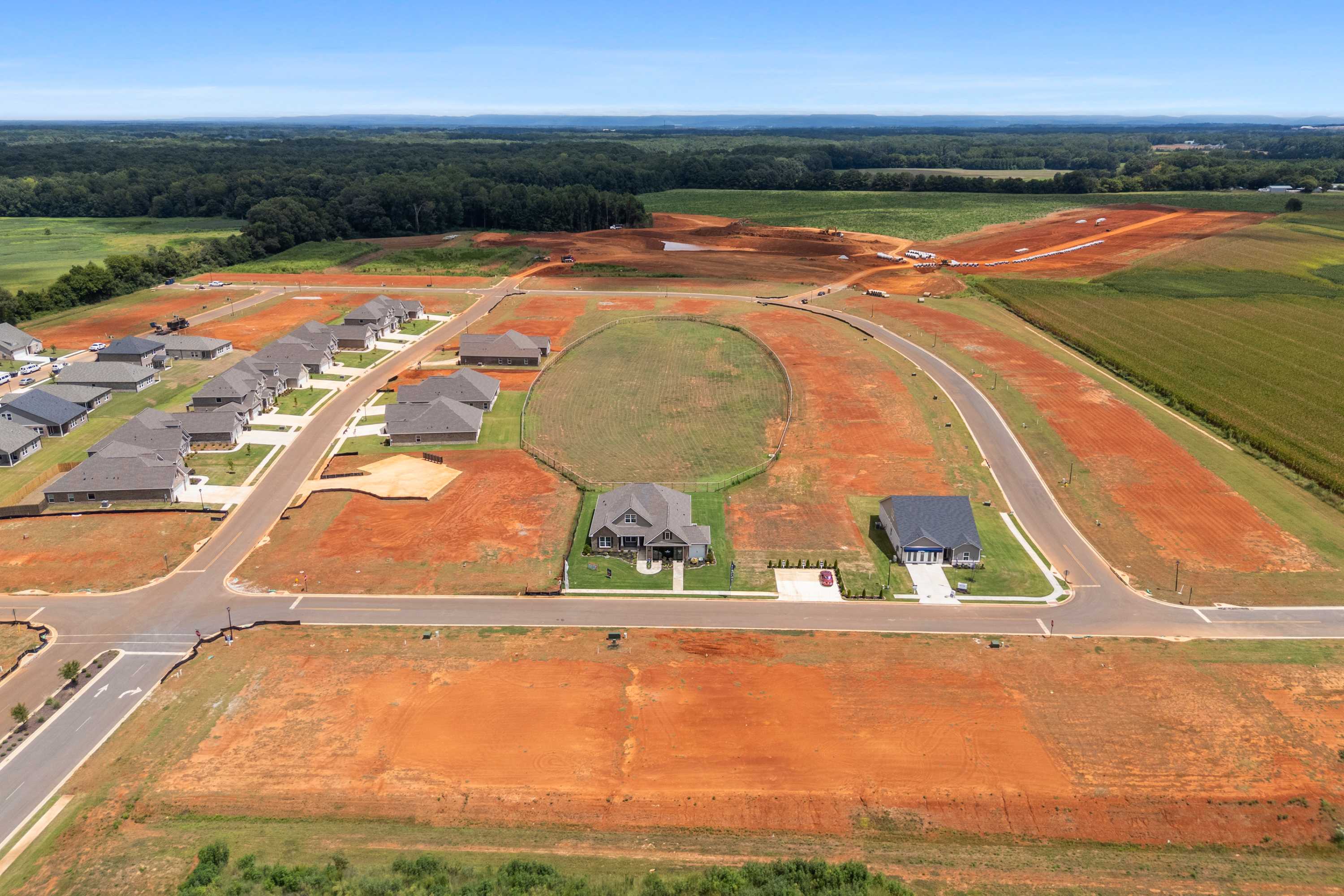 Aerial view of new homes in Kendall Farms Toney Alabama by Davidson Homes amid red dirt roads and surrounding green fields