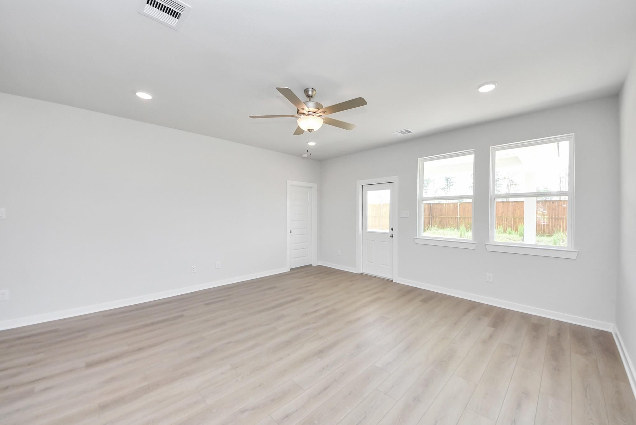 Bright, open-concept living area with wood-style flooring in The Blanco F floor plan at Spring Branch Crossing, Conroe.