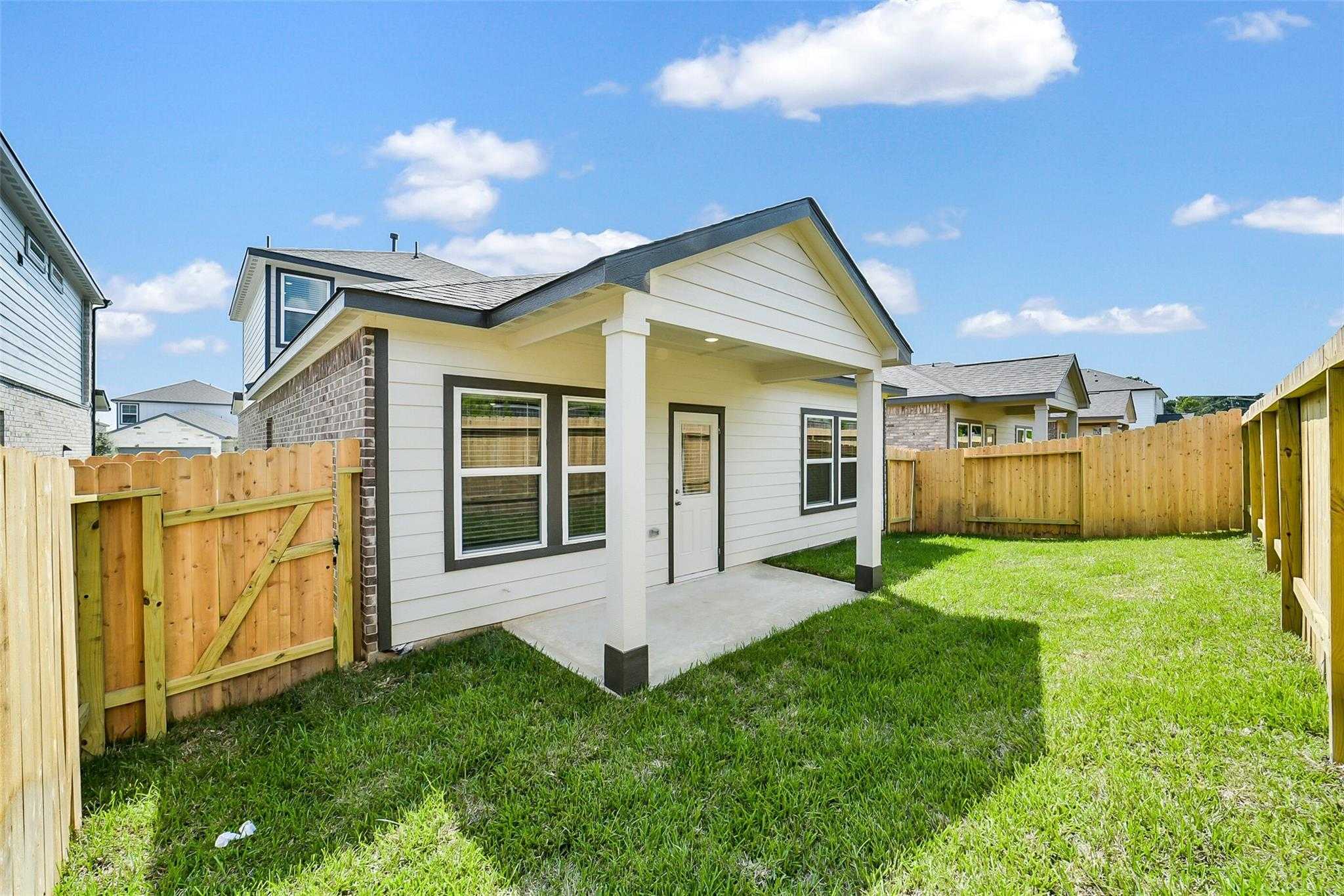 Covered back patio on Davidson Homes Blanco E with brick accents, large windows, fenced green yard in Lakes at Black Oak, Magnolia, Texas