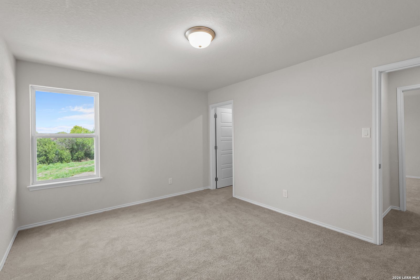 Spacious carpeted bedroom with natural light in The San Marcos F floor plan at Rayburn Valley, San Antonio, Texas.