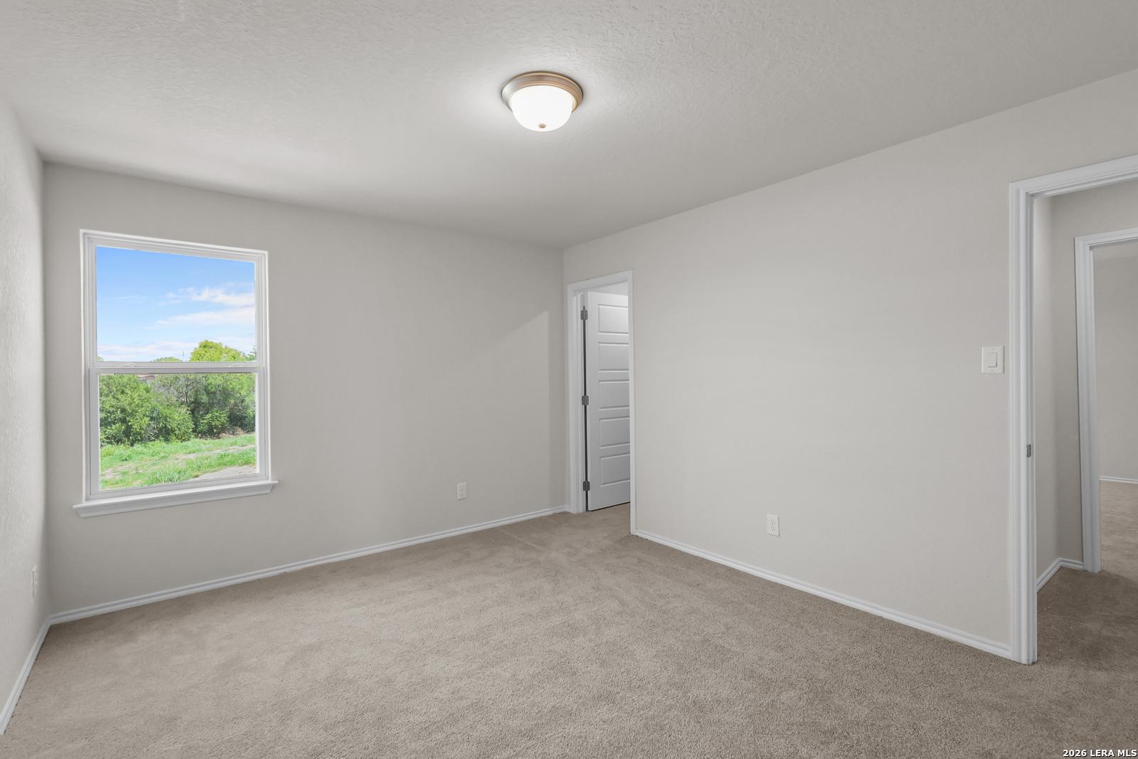 Spacious carpeted bedroom with natural light in The San Marcos F floor plan at Rayburn Valley, San Antonio, Texas.