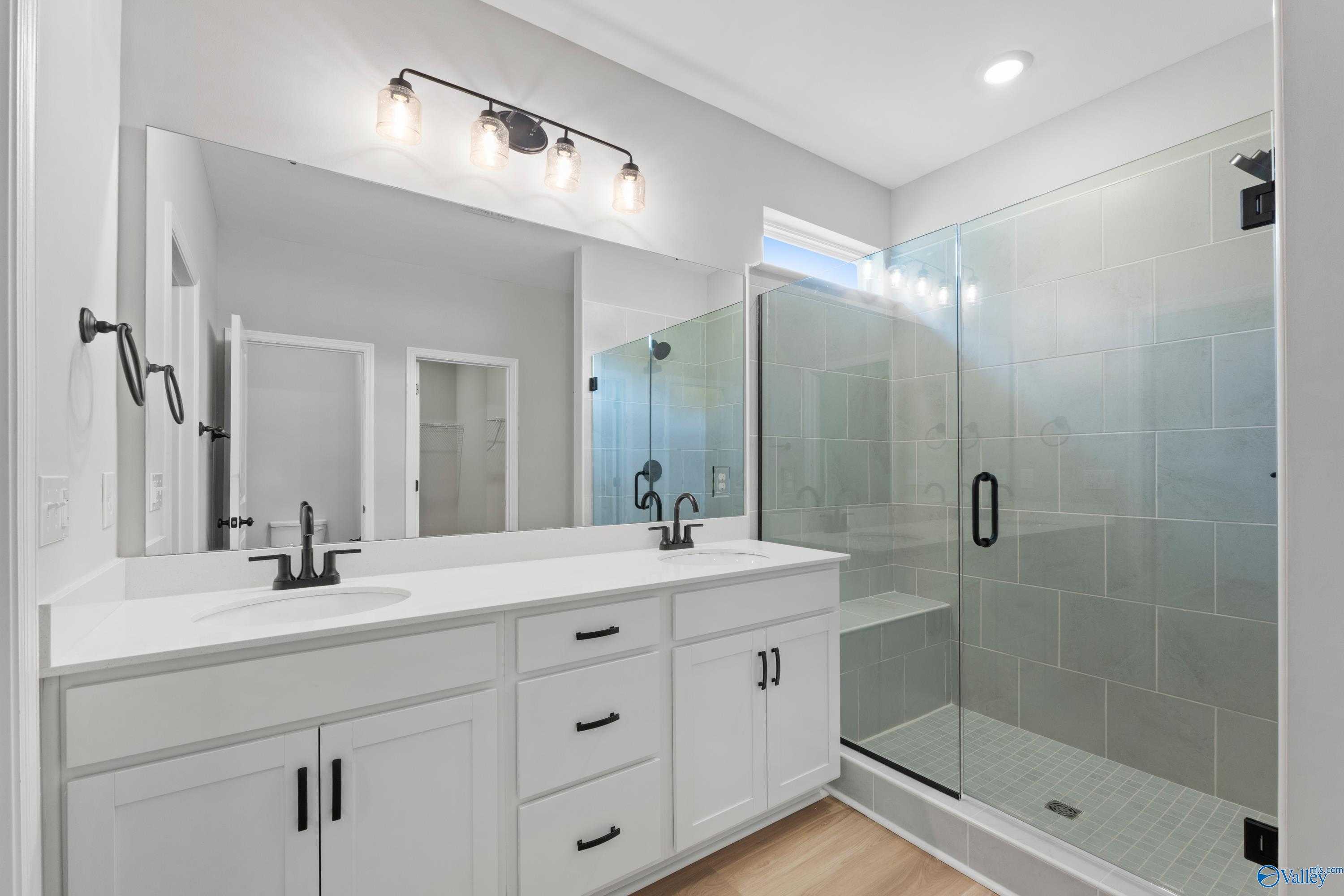 Modern master bathroom featuring double vanity, frameless glass shower, and subway tile in Davidson Homes The Phoenix, Hazel Green, Alabama