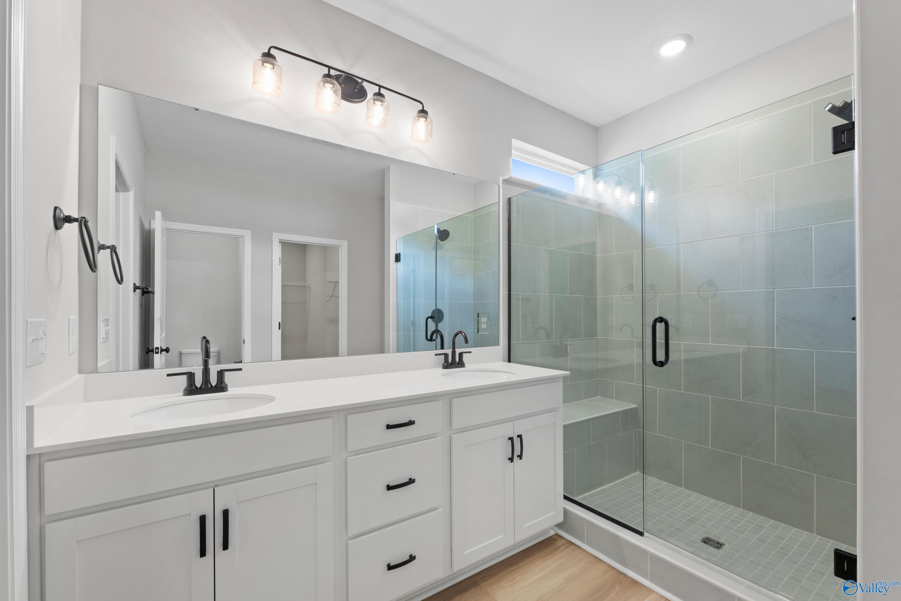 Modern master bathroom featuring double white vanity, glass shower with subway tiles in Davidson Homes The Phoenix, Hazel Green, AL
