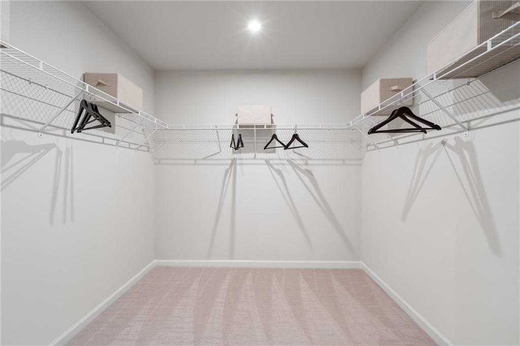 Spacious walk-in closet with wire shelving, hanging rods and beige carpet in Davidson Homes The Marion C, Winder, GA