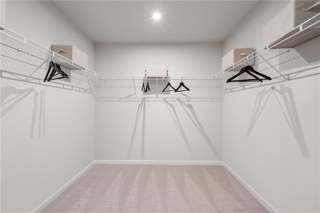 Spacious walk-in closet with wire shelving, hanging rods, and light carpet in Davidson Homes The Marion B, Kennesaw, Georgia