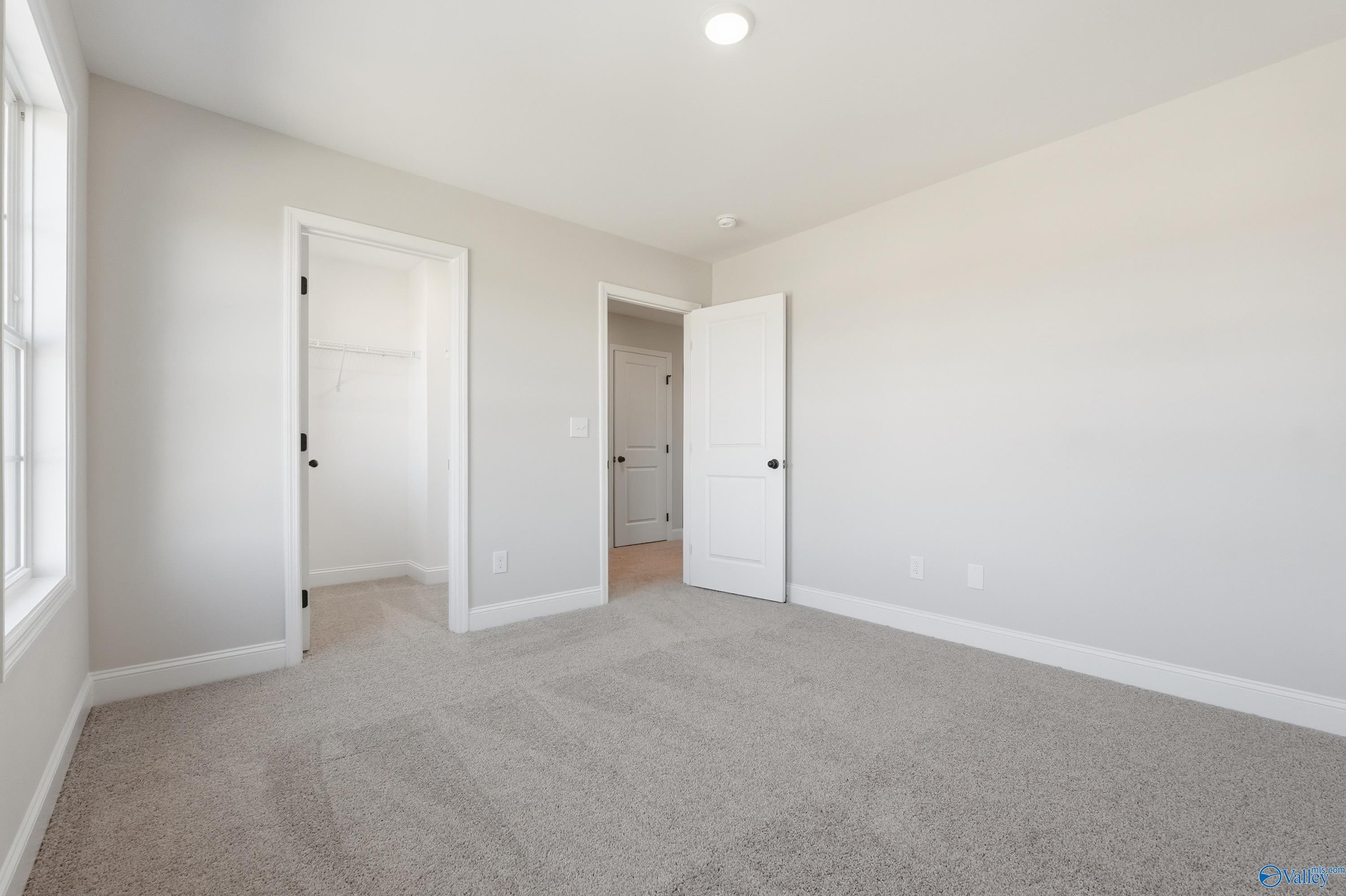 Spacious bedroom with walk-in closet, neutral carpet and walls in Davidson Homes Chelsea C, Creekside, Harvest, AL