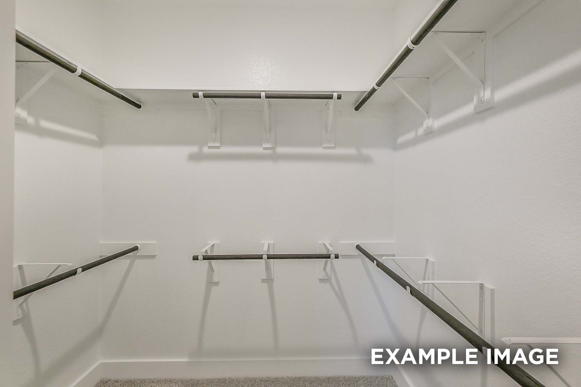 Spacious walk-in closet in The Luna K master suite with gray hanging rods and white walls