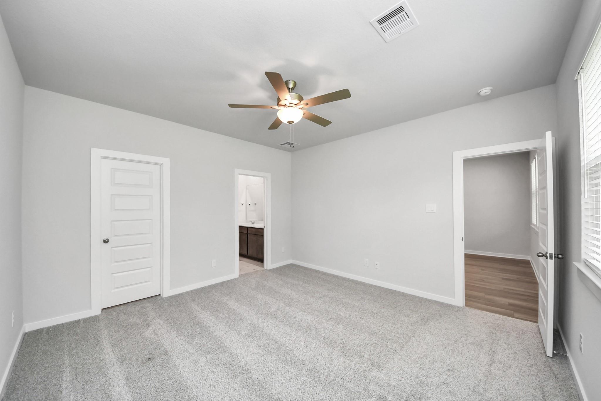 Spacious secondary bedroom with ceiling fan and plush carpeting in The Sabine E floor plan at Liberty Estates, Cleveland.
