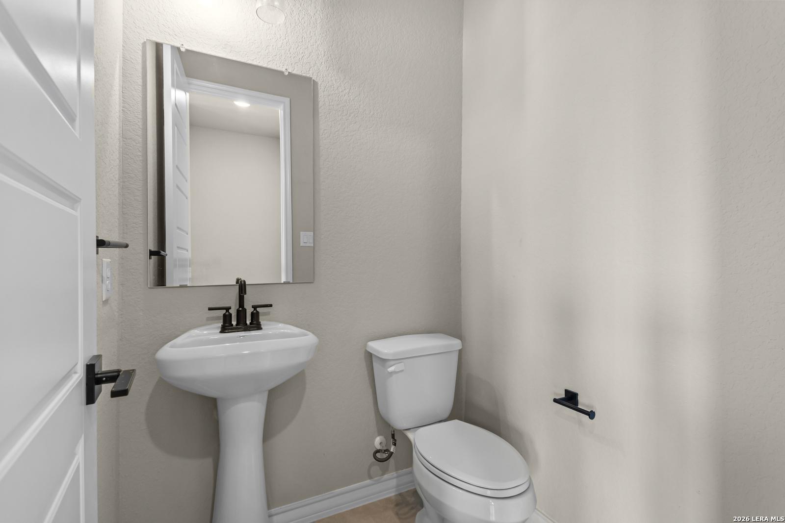 Modern powder room with pedestal sink in The Danbury H floor plan at The Reserve at Potranco Oaks, Castroville, Texas.