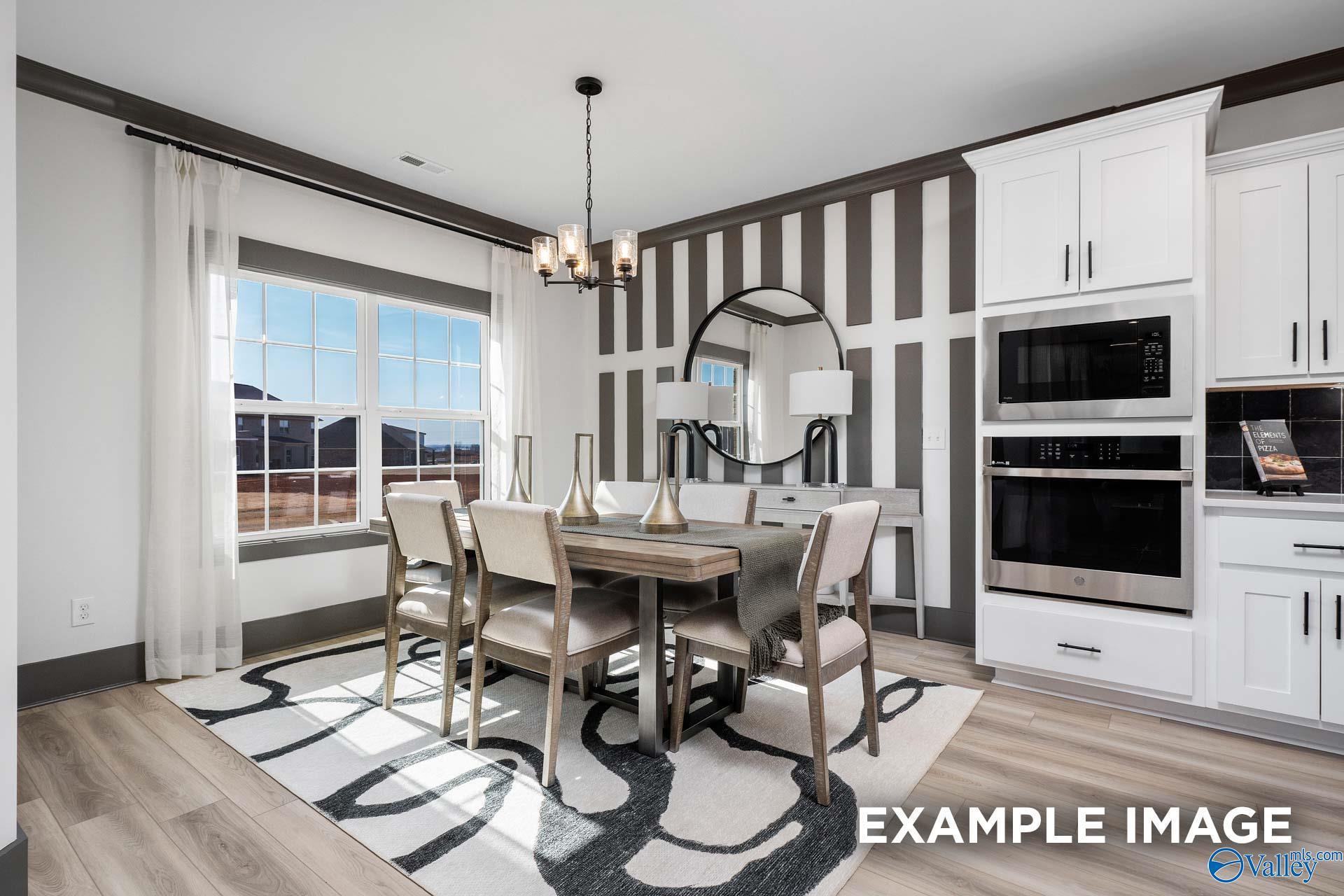 Elegant dining room with chandelier, round mirror, striped walls, and white kitchen cabinets in Davidson Homes The Rockford B, Madison, Alabama