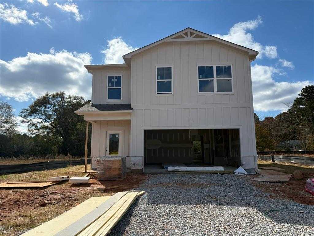 Two-story white shiplap Rabun C home by Davidson Homes in Cedar Farms, Winder, GA: open 2-car garage, front porch, pine backdrop