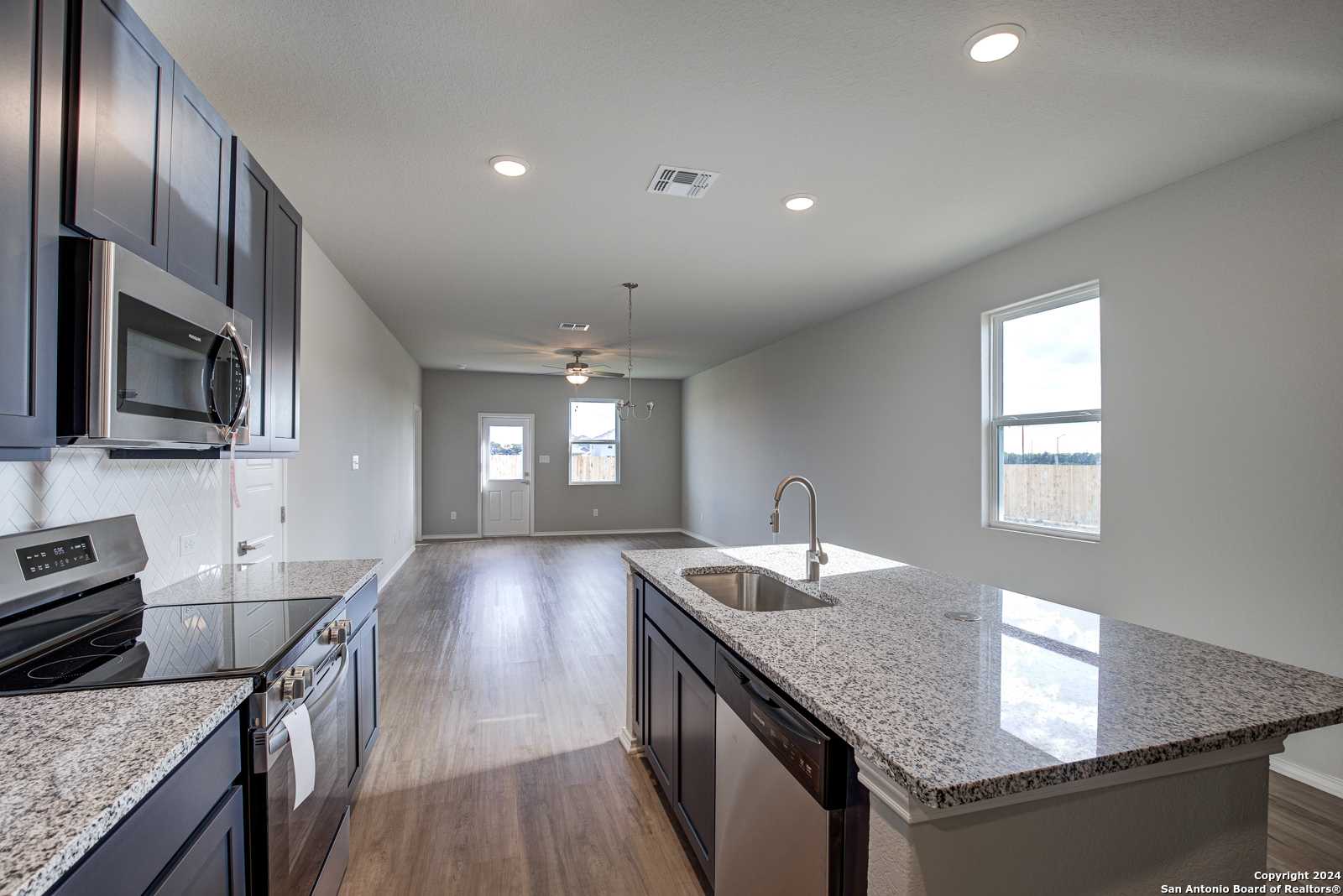 Modern open kitchen with dark cabinets, granite island sink, stainless appliances in Davidson Homes The Frio B, San Antonio