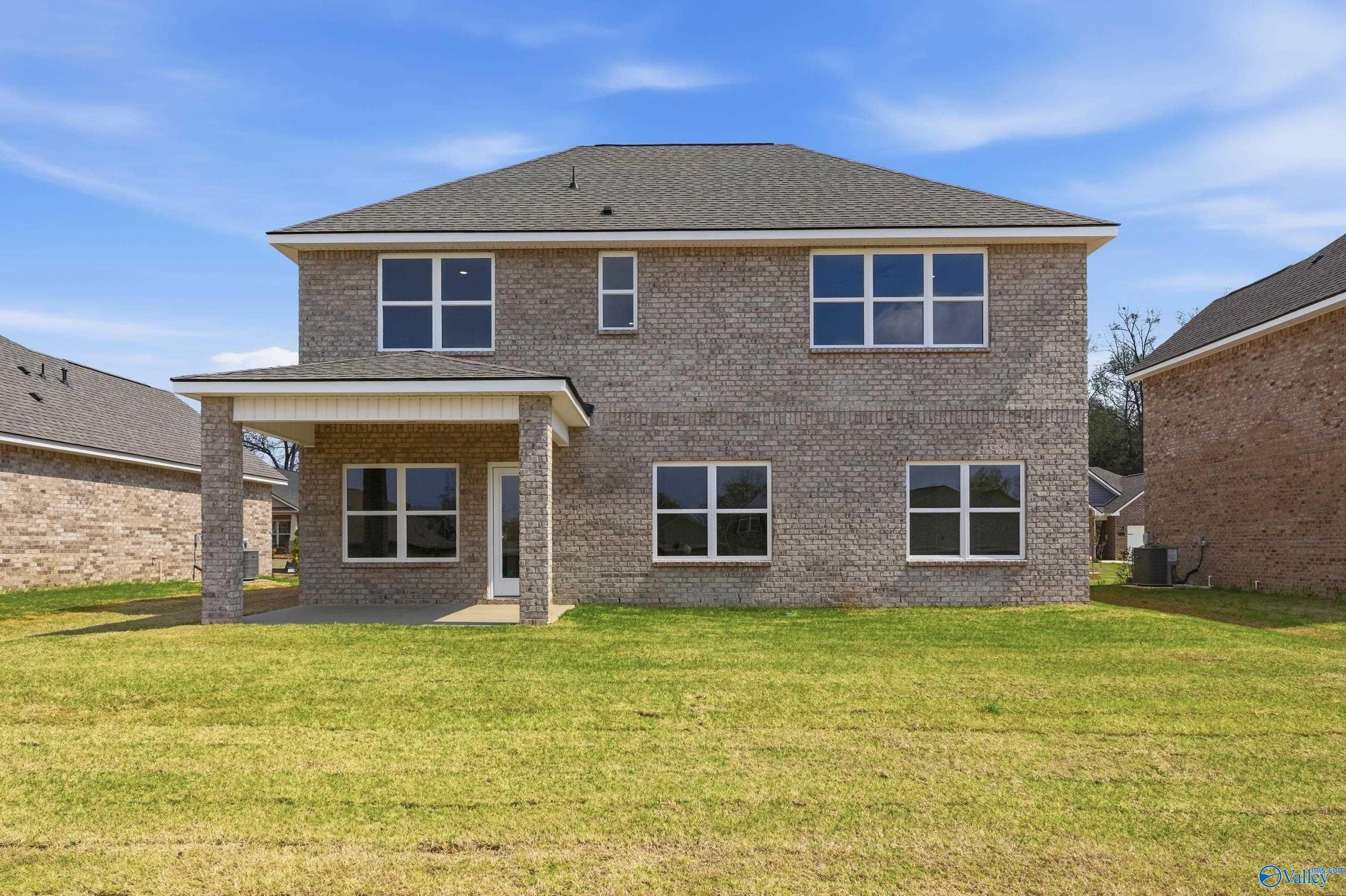 Two-story brick home with covered back patio, large windows, and lush grassy yard in Creek Grove, New Market, Alabama - Davidson Homes Shelby B