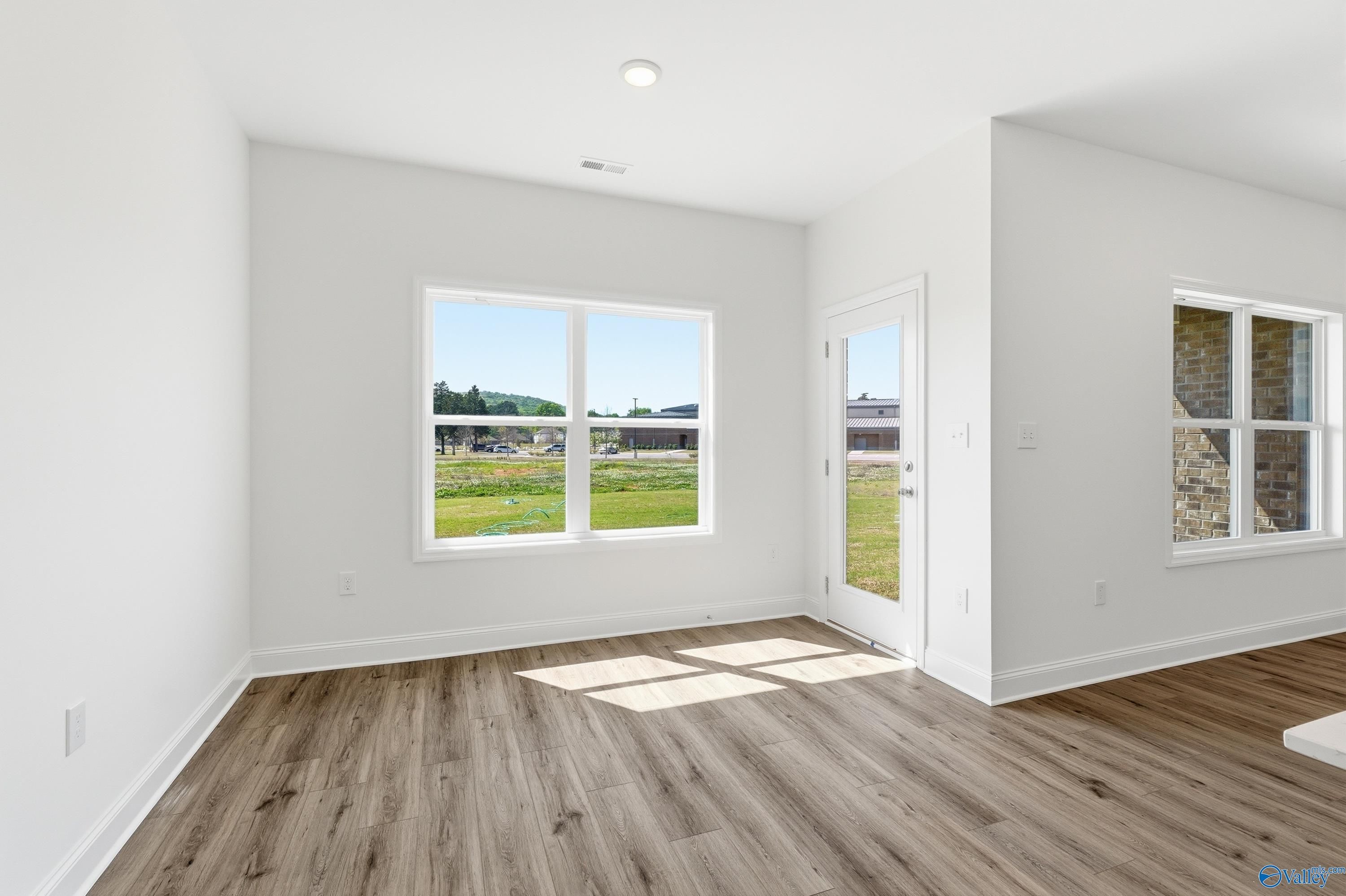 Bright, open-concept living area with wood-style flooring in The Asheville floor plan at Jaguar Hills, Huntsville, Alabama.
