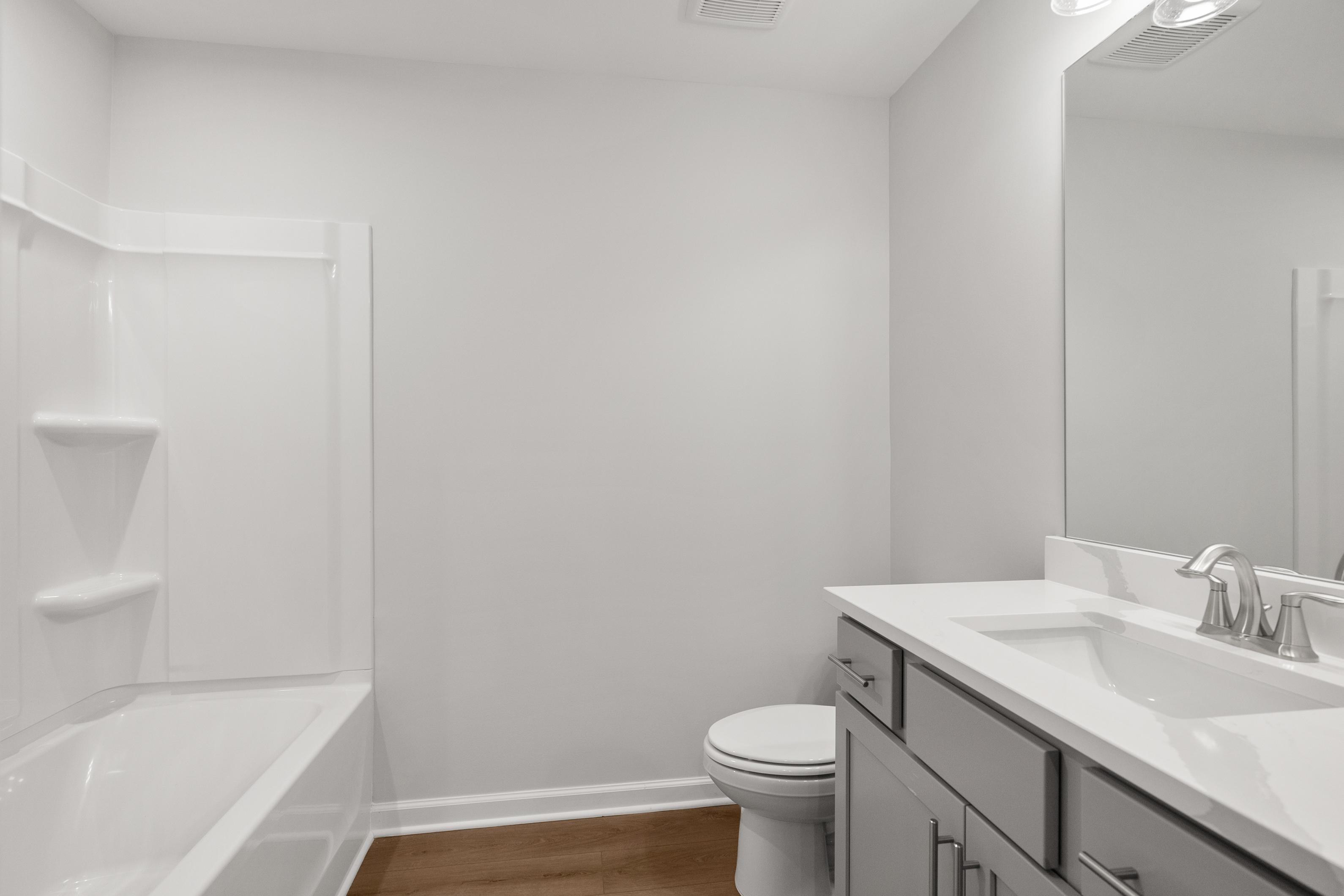Spacious white bathroom in The Durant A by Davidson Homes with soaking tub, double vanity sink, mirror, and hardwood floors