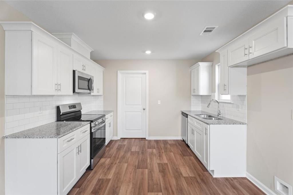 White shaker cabinet kitchen with granite counters, subway tile backsplash, stainless appliances in Davidson Homes The Washington, Phenix City