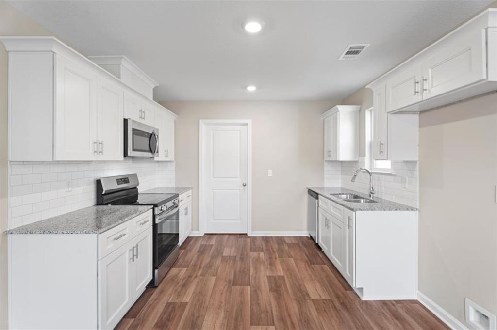White shaker cabinet kitchen with granite counters, subway tile backsplash, stainless appliances in Davidson Homes The Washington, Phenix City