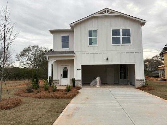 Two-story white farmhouse-style home with gabled roof, open 2-car garage, front porch, and landscaped yard in Cedar Farms, Winder, Georgia - Davidson Homes Rabun C
