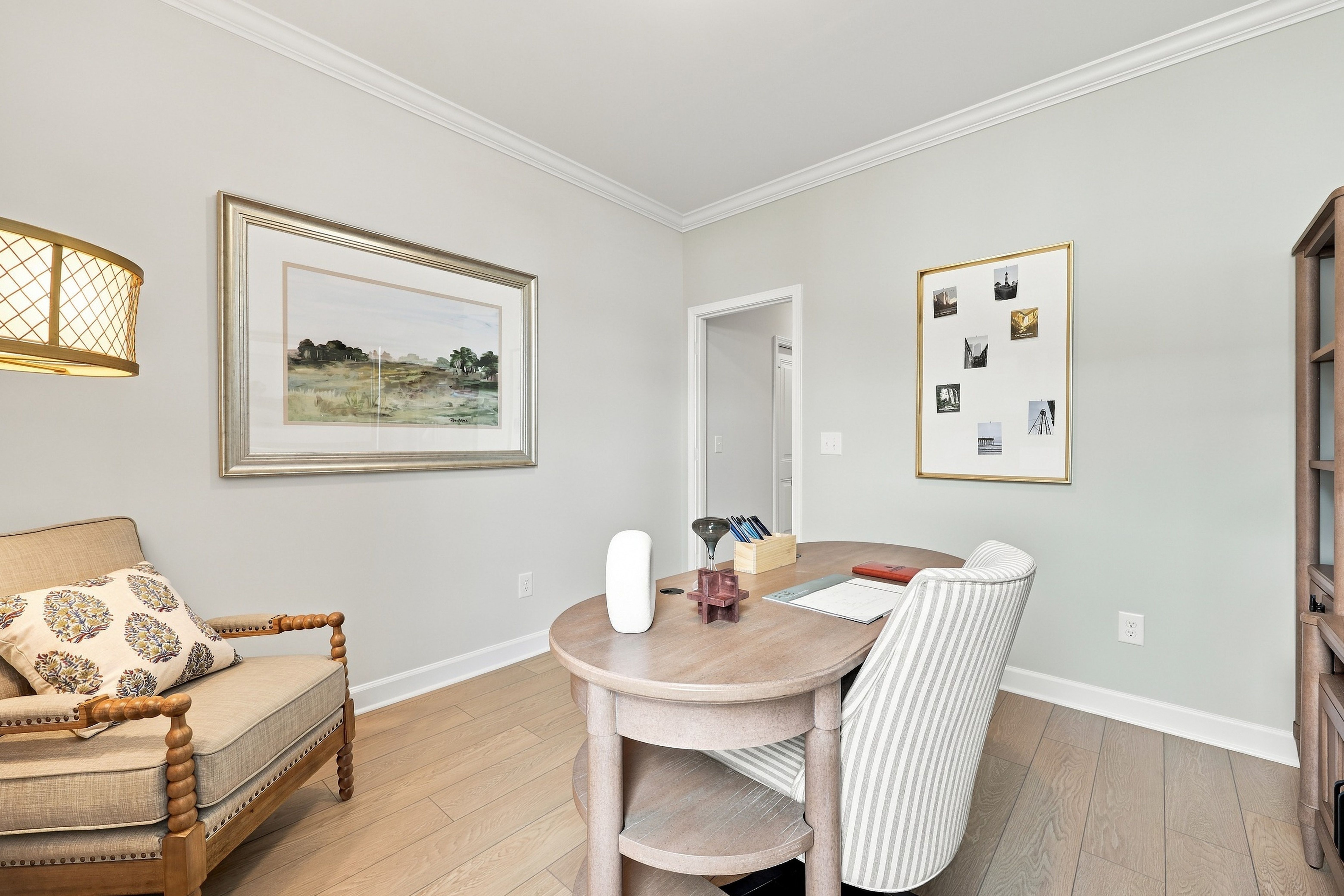 Bright home office in The Daphne D featuring a wooden desk, upholstered armchair, and light hardwood flooring.