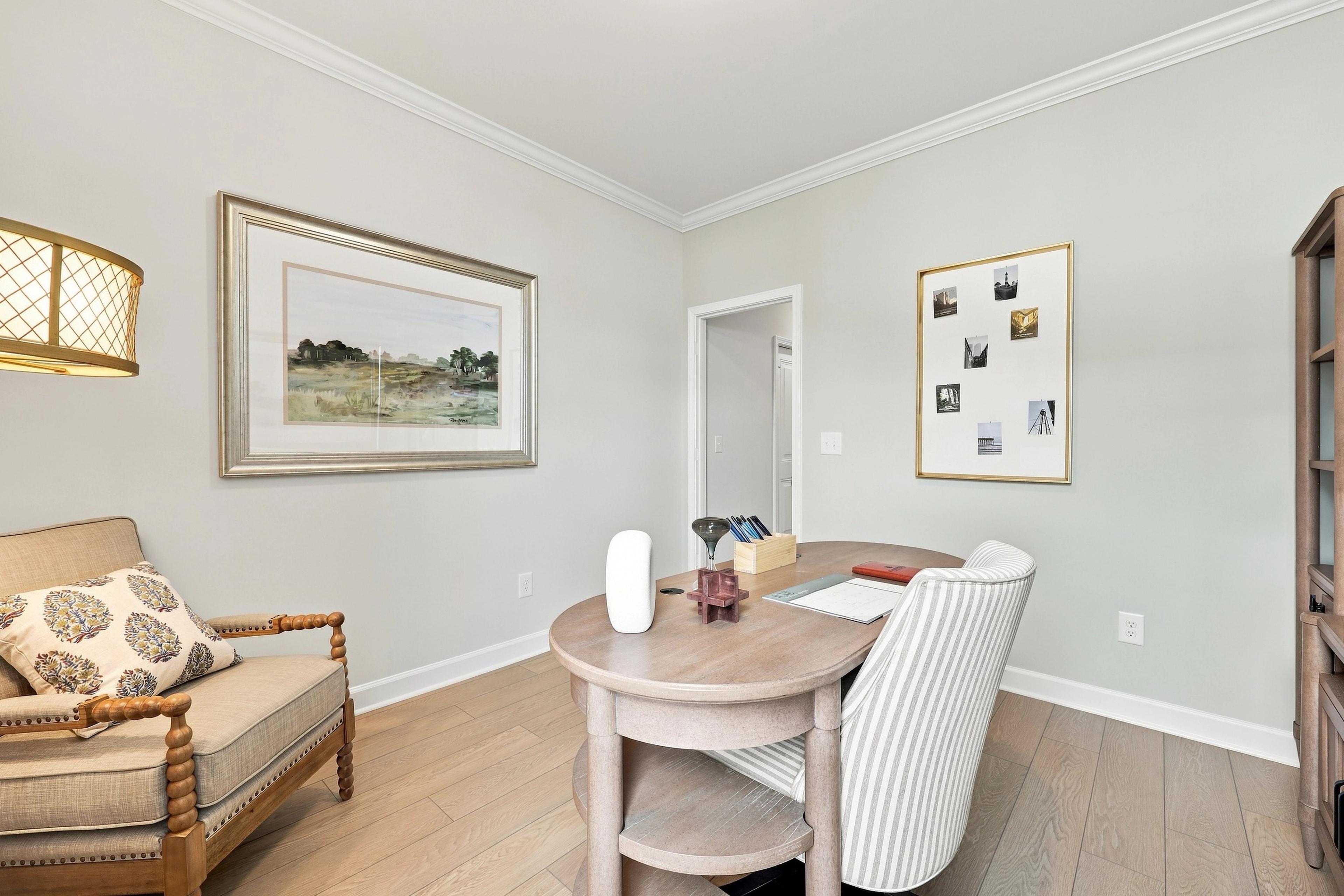 Bright home office in The Daphne D featuring a wooden desk, upholstered armchair, and light hardwood flooring.