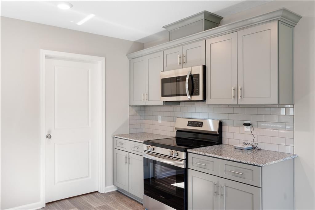 Modern kitchen with gray cabinets, granite countertops, and stainless appliances in The Washington home, Phenix City, AL.