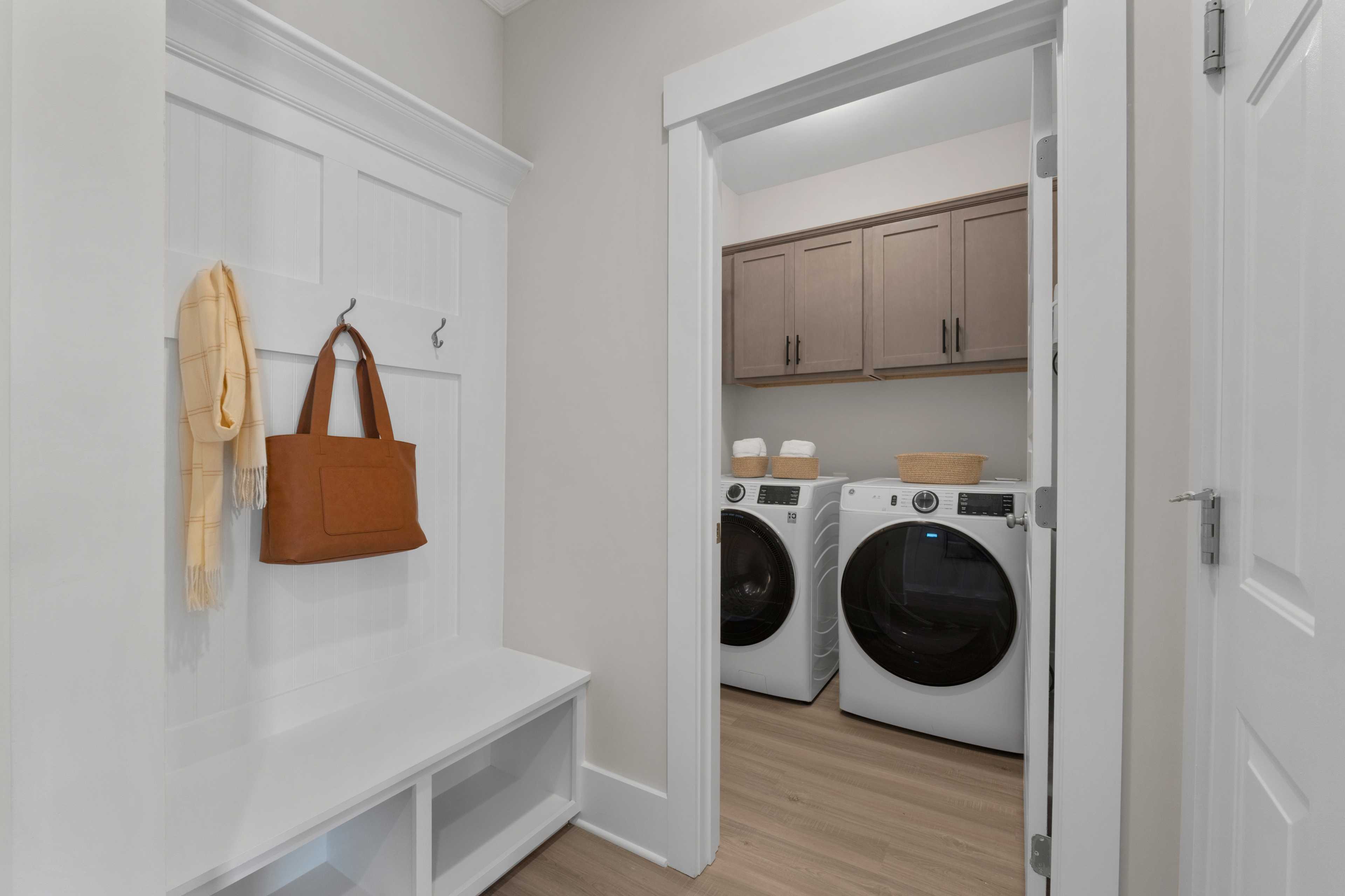 Spacious mudroom and laundry room at Hollon Meadow in Decatur Alabama with white bench hooks shaker cabinets and washer dryer