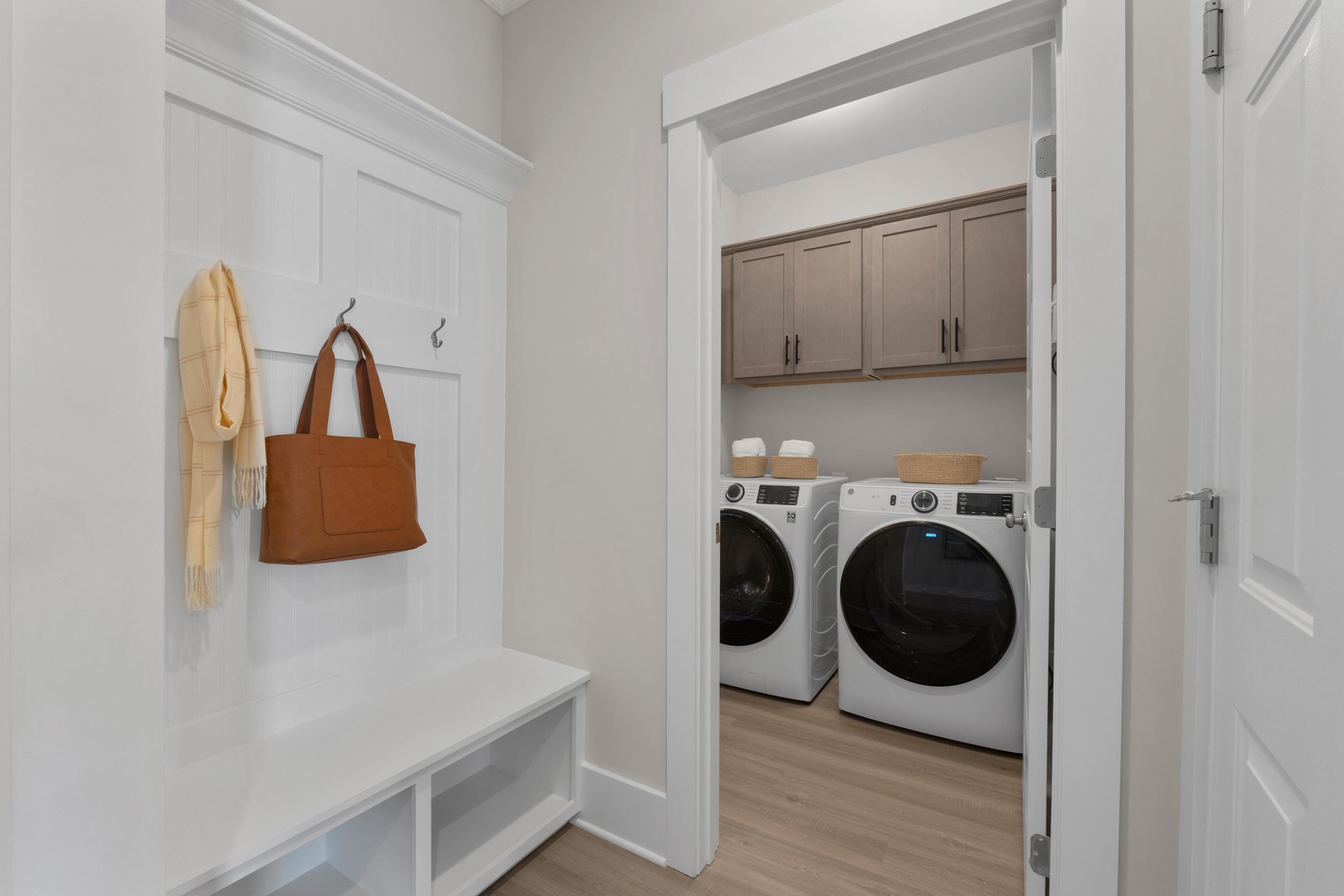 Spacious mudroom and laundry room at Hollon Meadow in Decatur Alabama with white bench hooks shaker cabinets and washer dryer