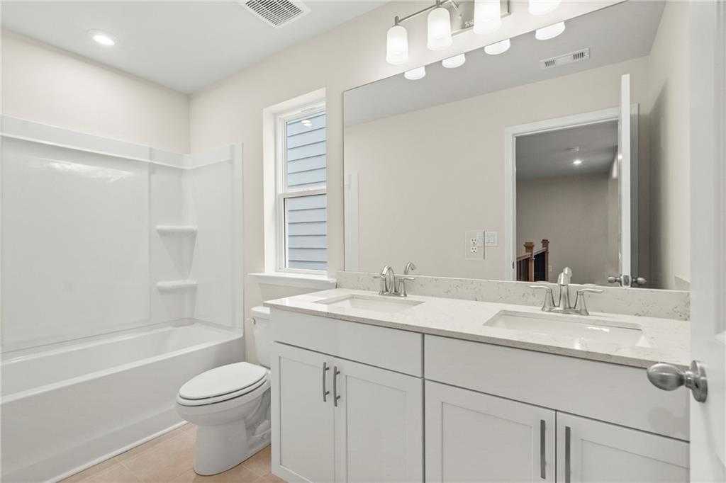 Modern master bathroom with double vanity, soaking tub, large mirror, and subway tile in Davidson Homes The Cary A, Kennesaw, Georgia