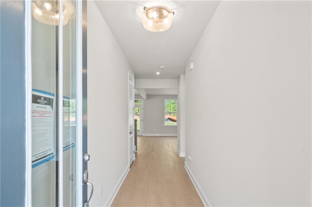Bright entry hallway with light oak floors, white walls, and glass front door in Davidson Homes The Hickory E, Buford, GA