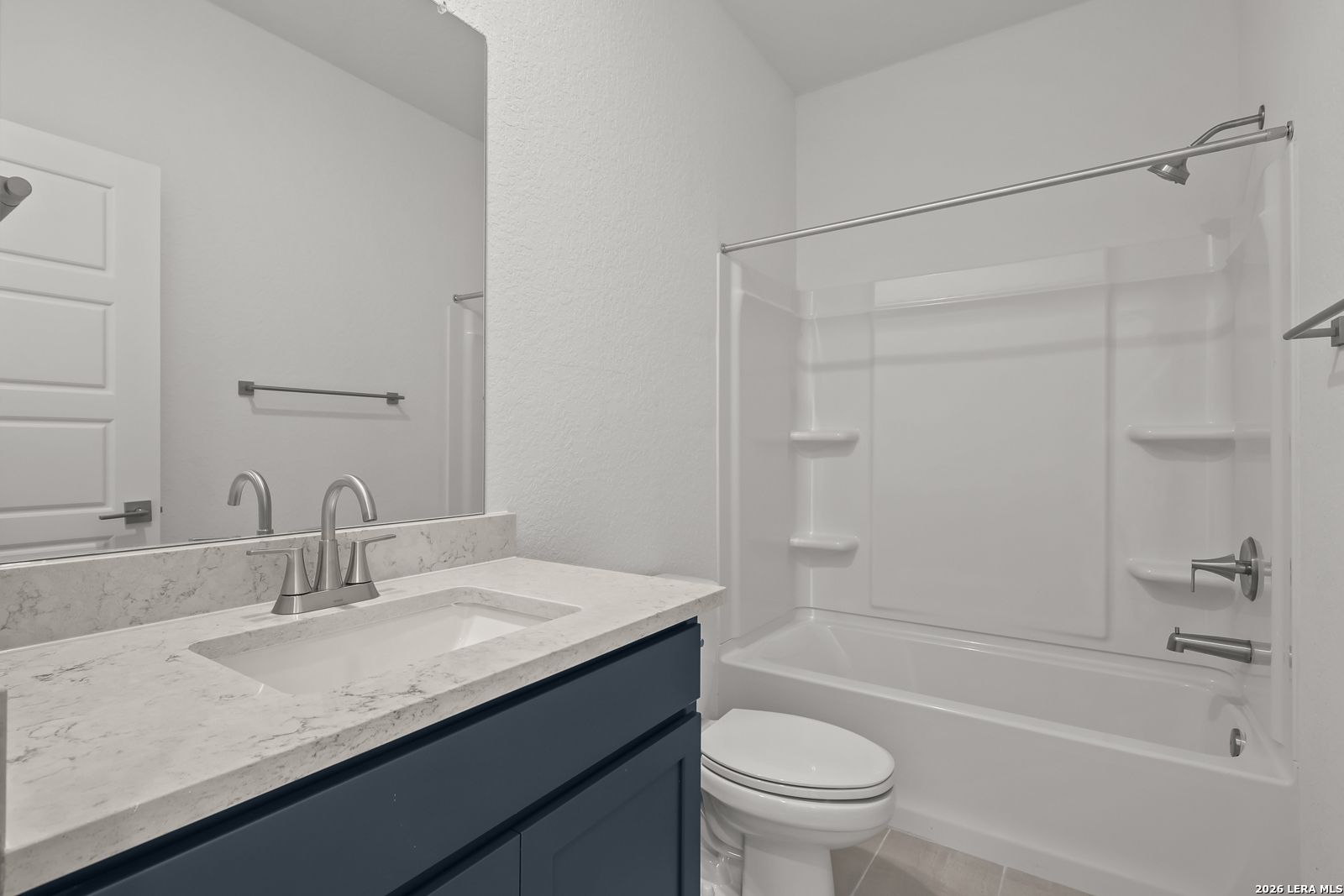 Modern bathroom with white vanity, marble-style countertop, and tub-shower combo in The Gillian C home, San Antonio, Texas.