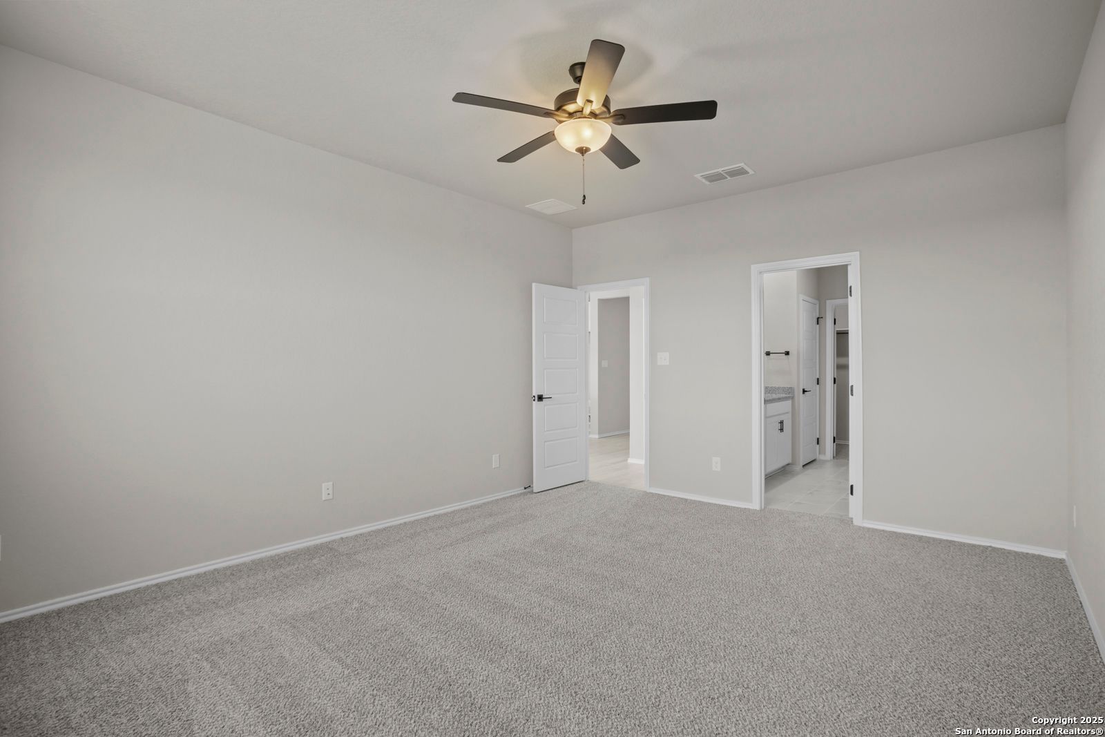 Spacious bedroom featuring ceiling fan, gray walls, carpet flooring, and en-suite bathroom in Davidson Homes The Daphne H, Seguin, Texas
