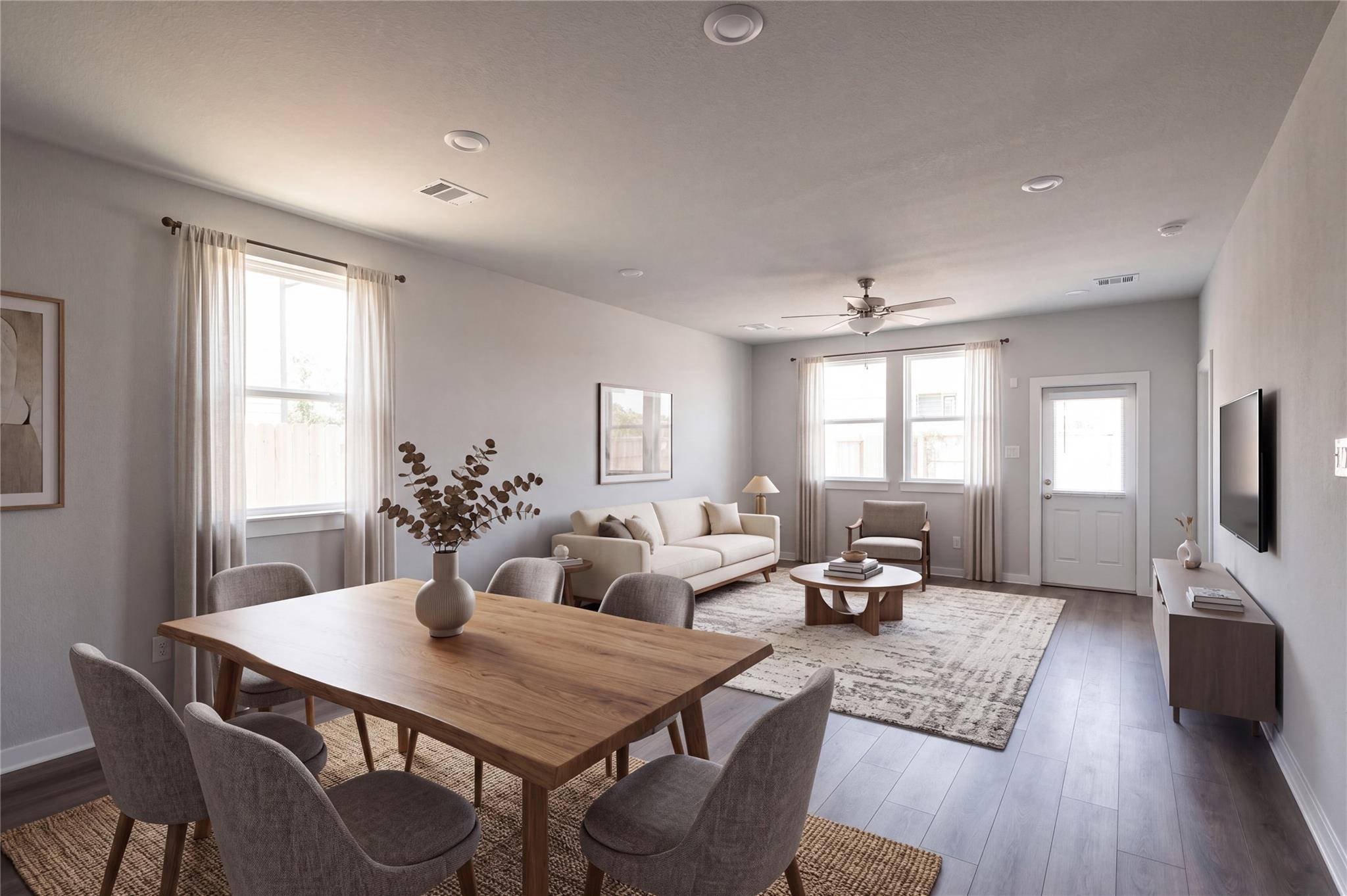 Open-concept dining and living area with wood table, plush seating, and ceiling fan in Davidson Homes The Frio F, Houston, Texas