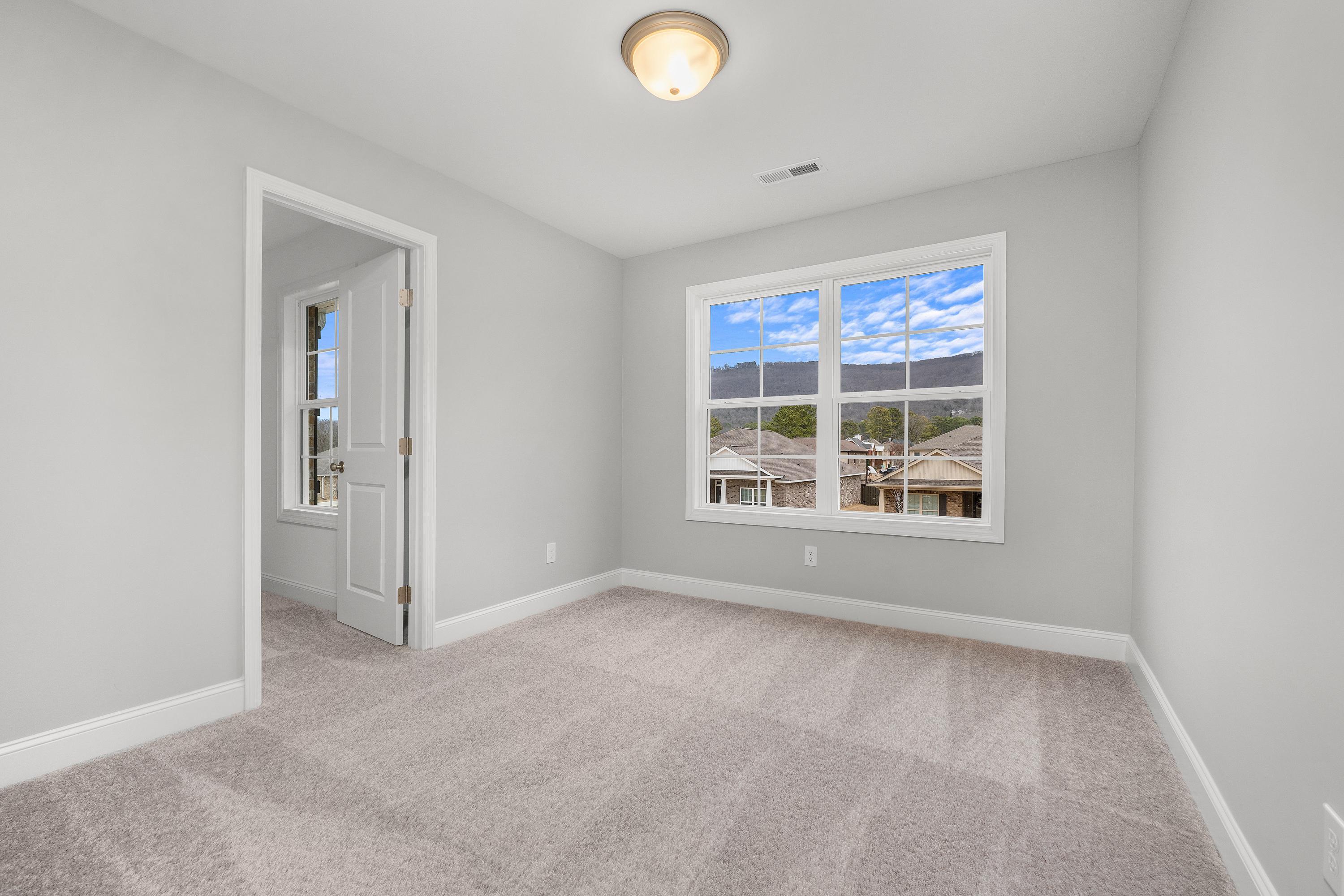 Upper floor bedroom in The Aiken by Davidson Homes, light gray walls, plush carpet, large window with neighborhood view