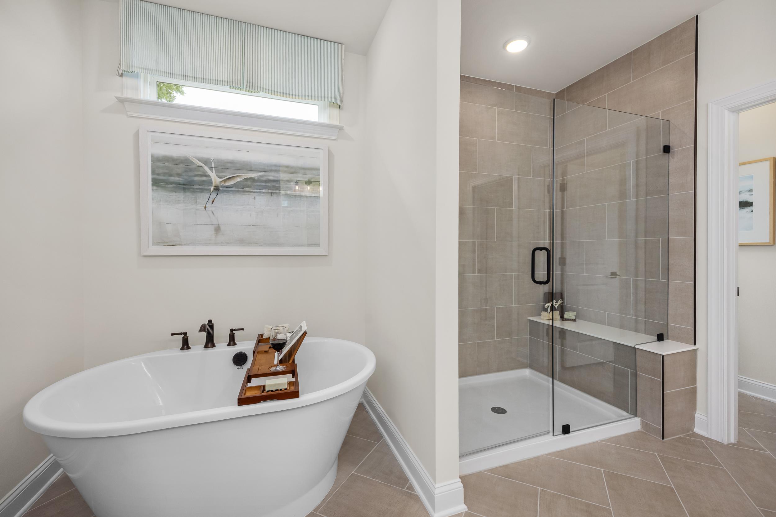 Spa-like master bathroom at Laneridge Estates in Raleigh NC with clawfoot tub, glass shower, and neutral tile