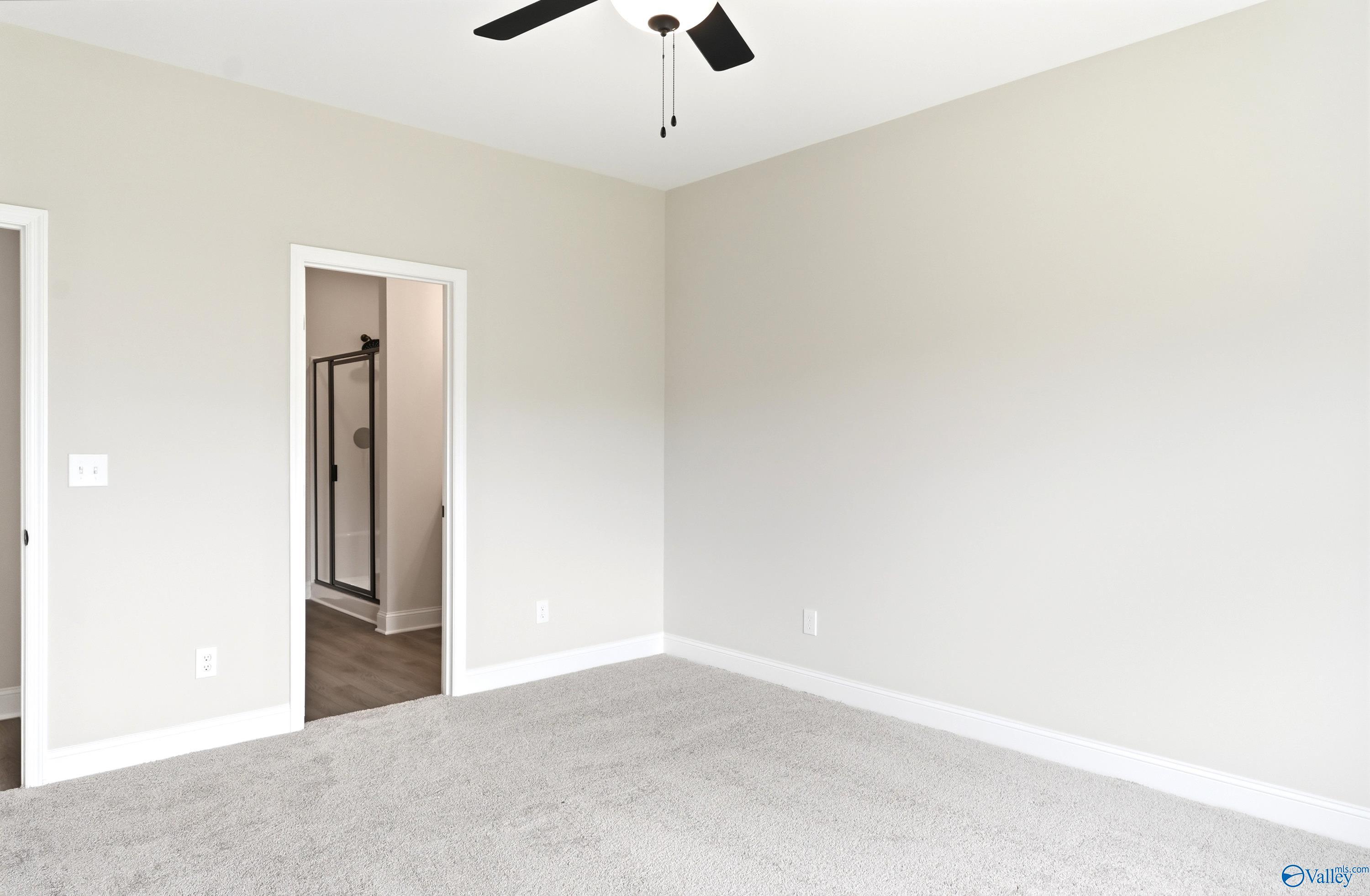 Spacious bedroom with neutral carpet and ceiling fan leading to an ensuite bathroom in The Daphne C floor plan, New Market.