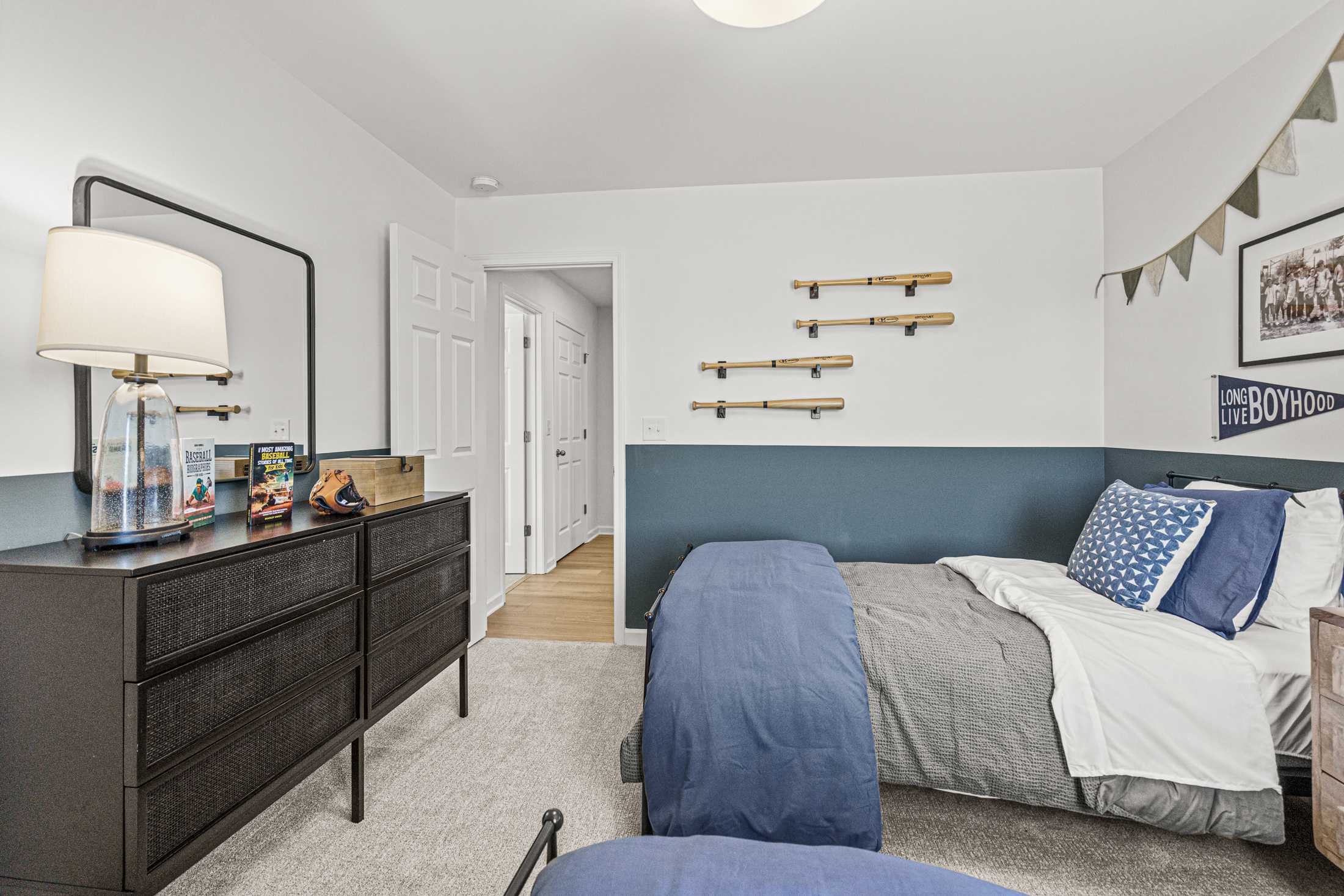 Cozy baseball-themed boy's bedroom at Cedar Farms in Winder Georgia with twin bed blue accent wall and black dresser