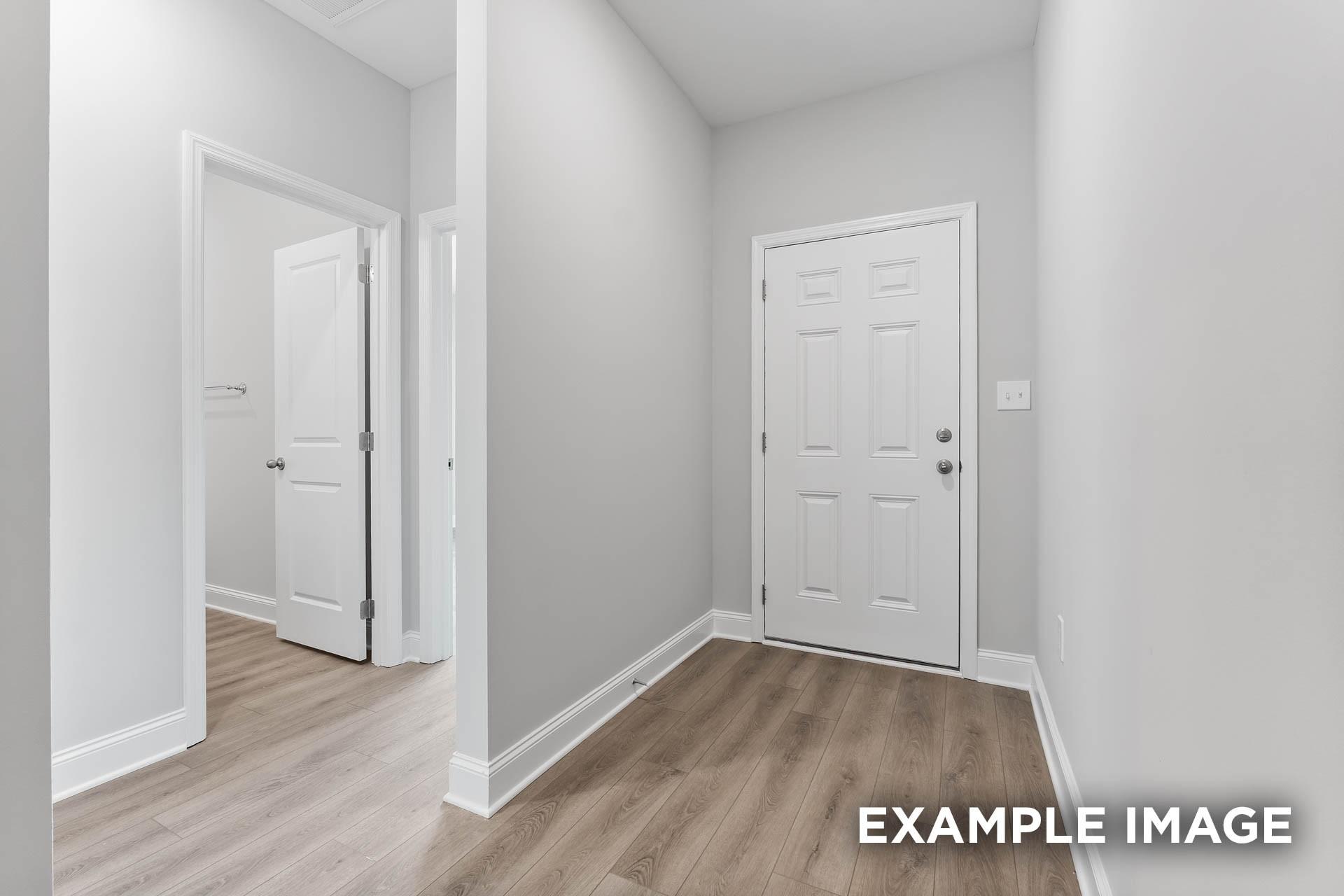 Bright entry hallway with white doors, gray walls, and laminate wood floors in Davidson Homes The Asheville E, Fayetteville, TN