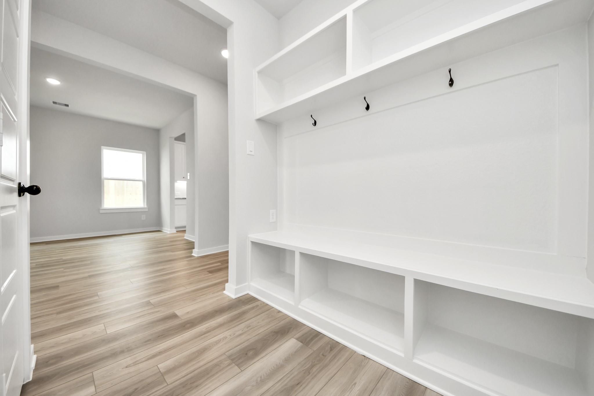 Built-in mudroom bench with storage and coat hooks in The Sorrento E floor plan by Davidson Homes in Sundance Cove, Texas.