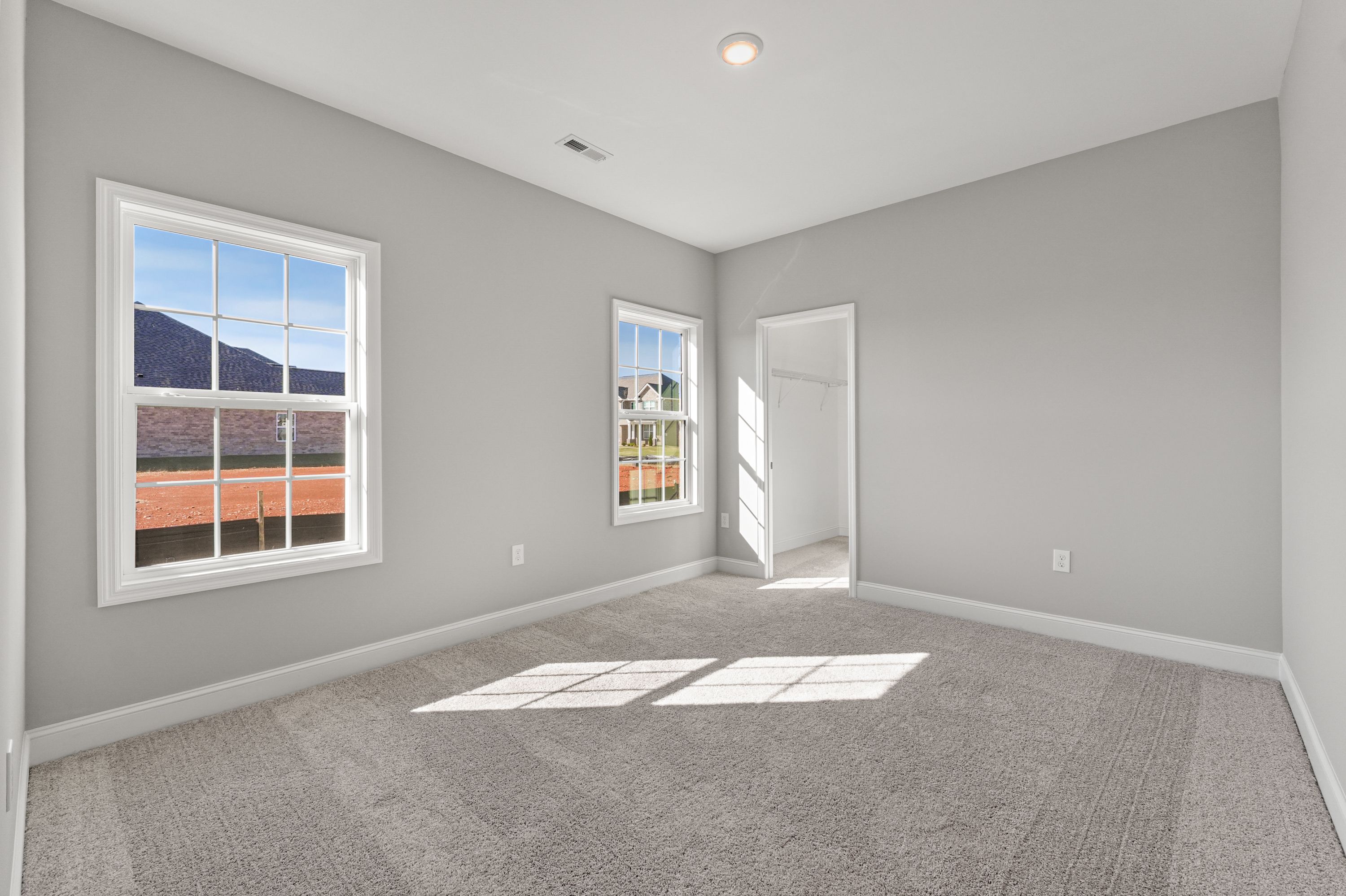 Spacious Valencia bedroom interior with light gray walls, neutral carpet, double windows showcasing mountain views